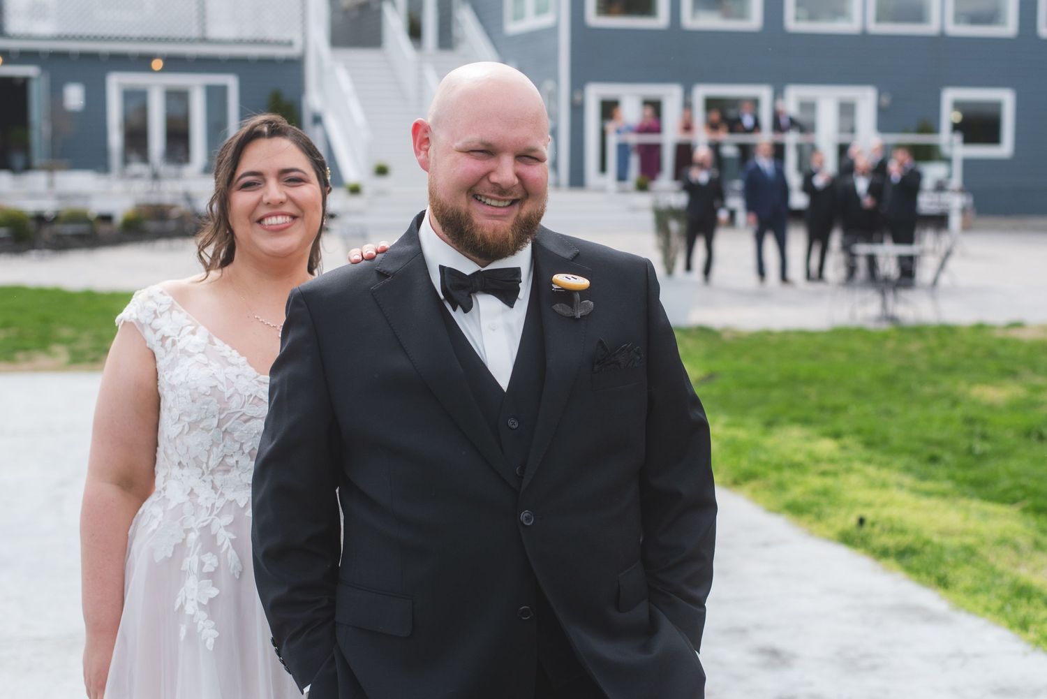 A bride and groom having a first look. The bride is laughing behind the groom.