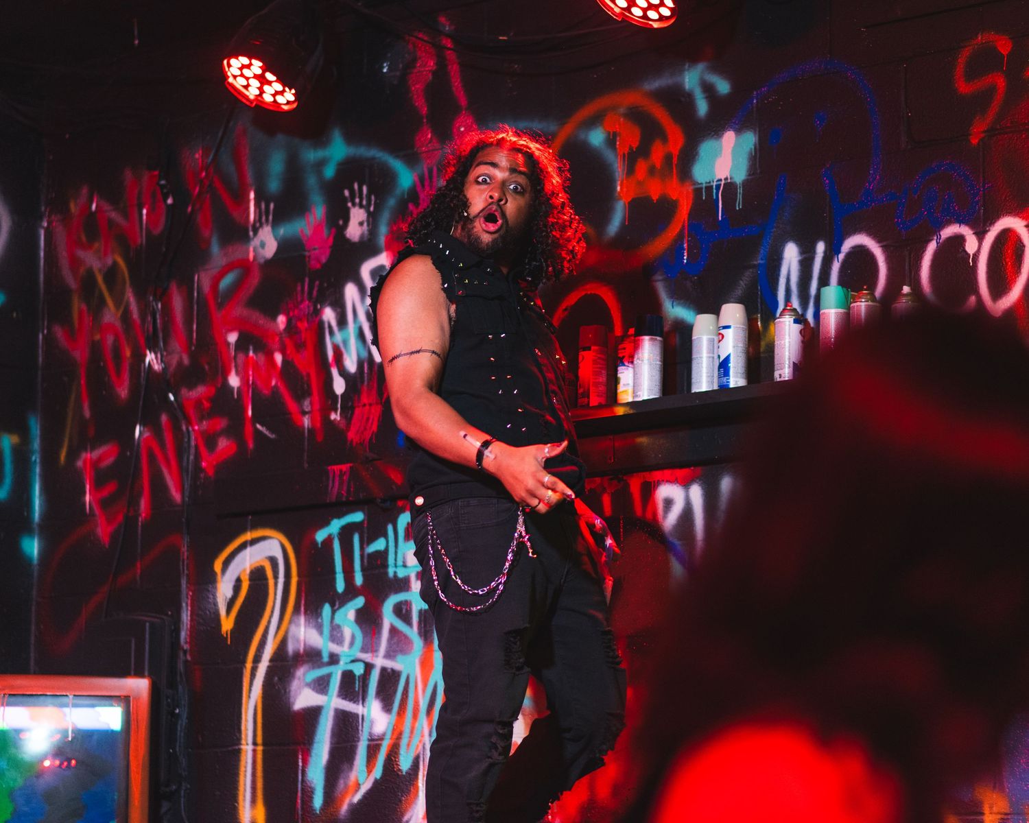 A photo from a production of American Idiot. The actor playing St. Jimmy is featured, the back wall is covered in graffiti.