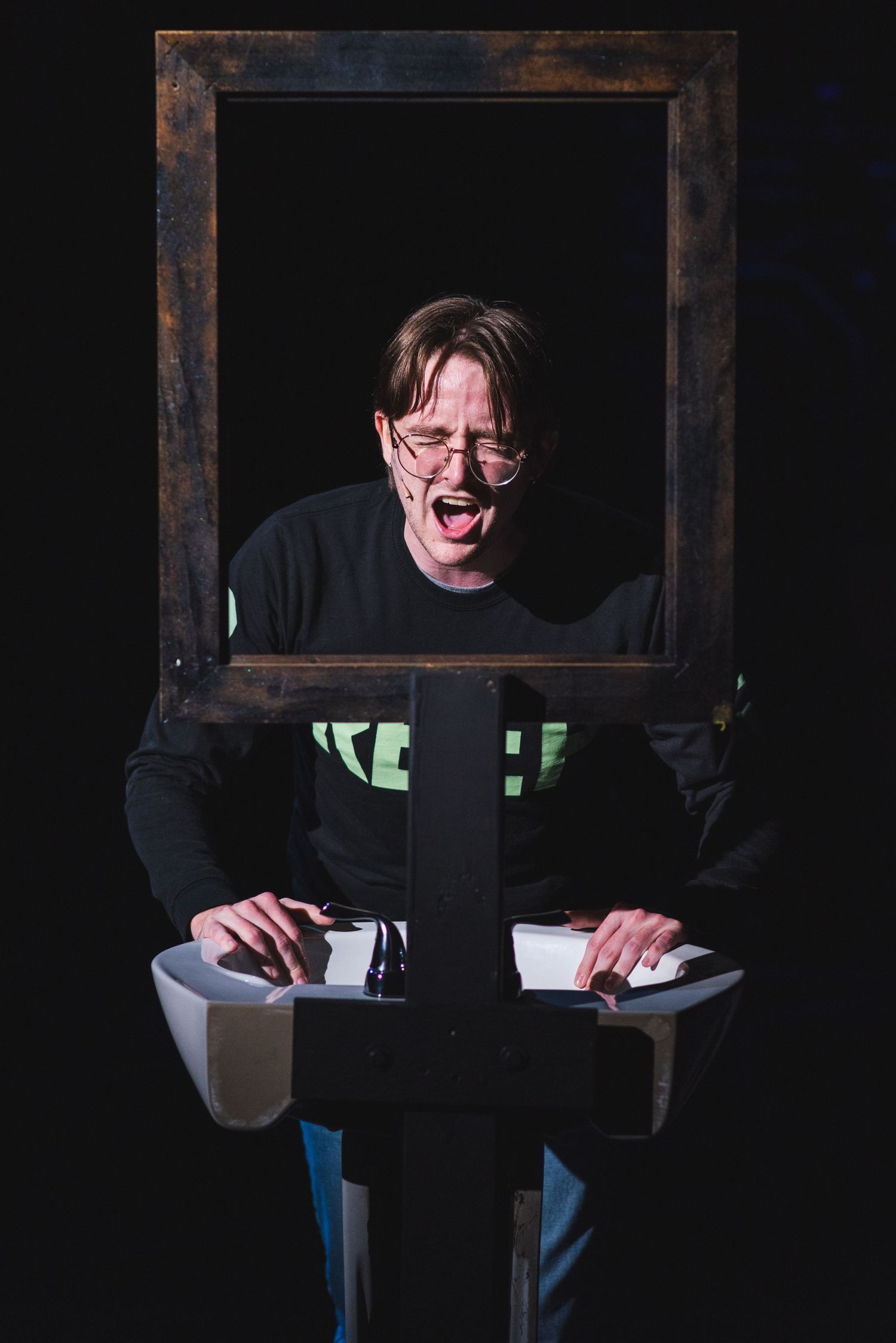 A photo from a production of Be More Chill. Michael is in the bathroom by himself.