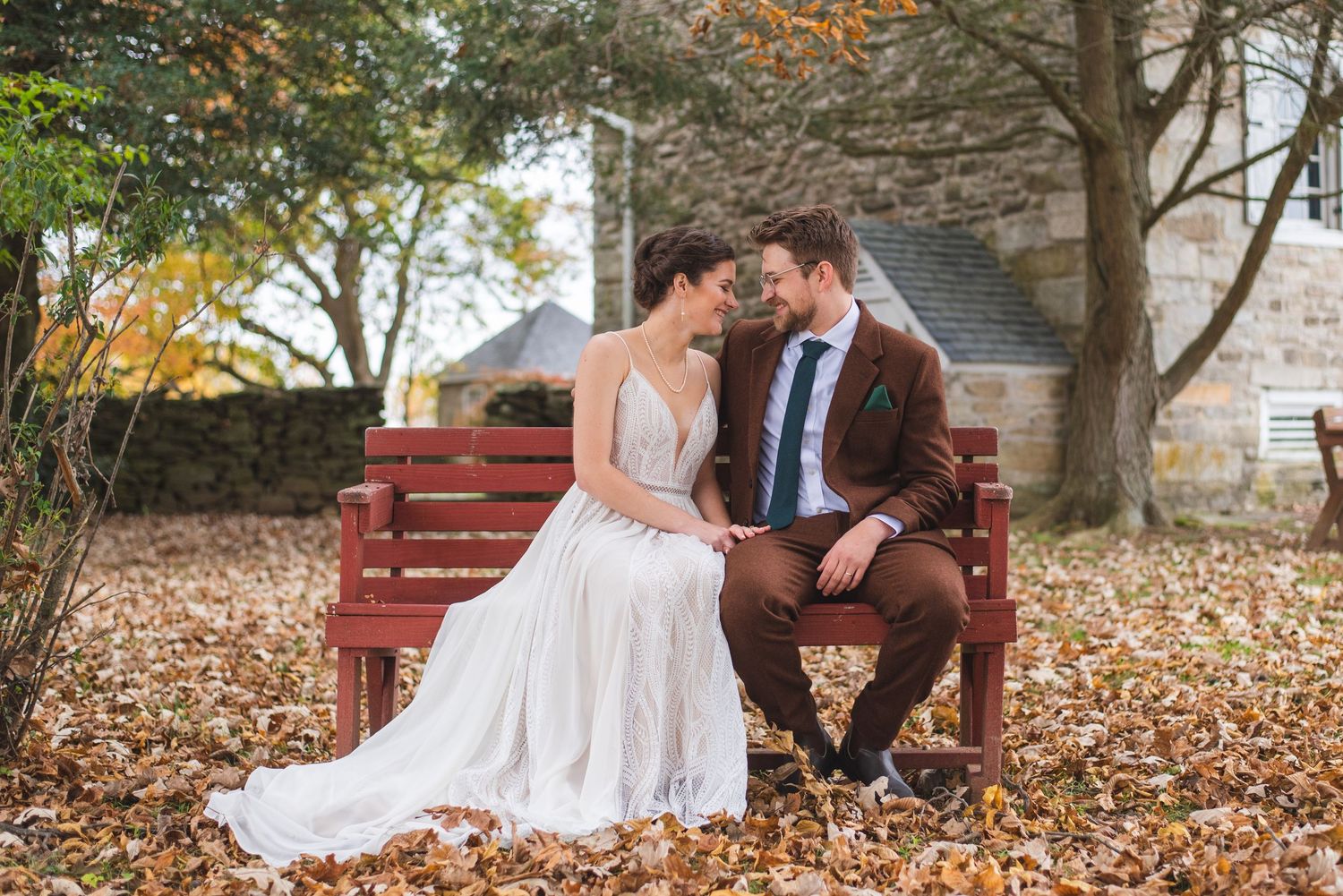 A newlywed couple posing on a park bench.