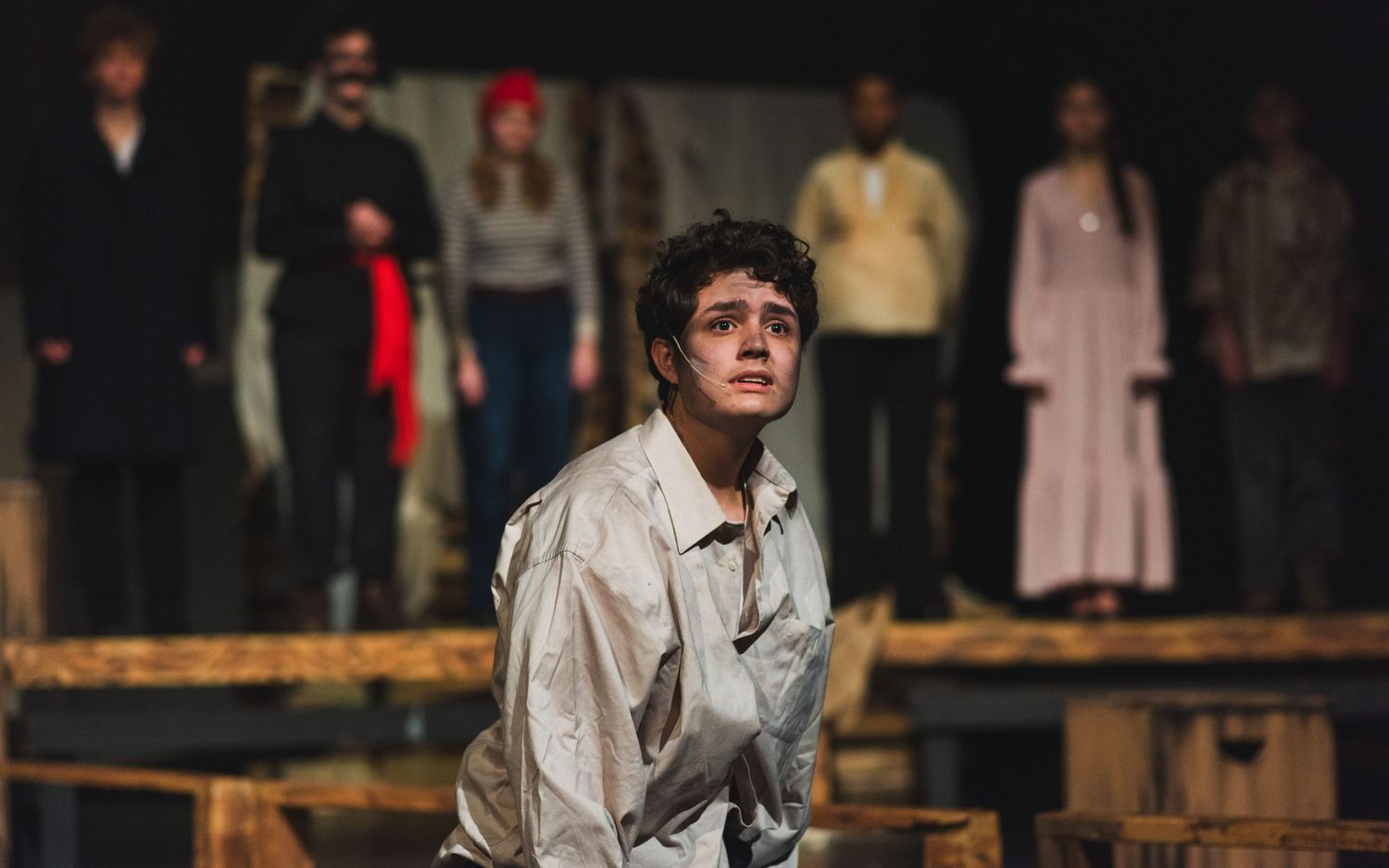 A photo from a production of Peter and the Starcatcher. The actor playing Peter is featured in the front of the photo, the ensemble behind.