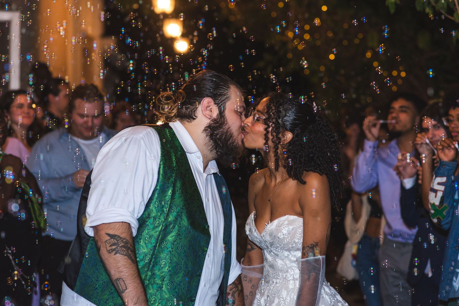 A newlywed couple kissing during a bubble exit.