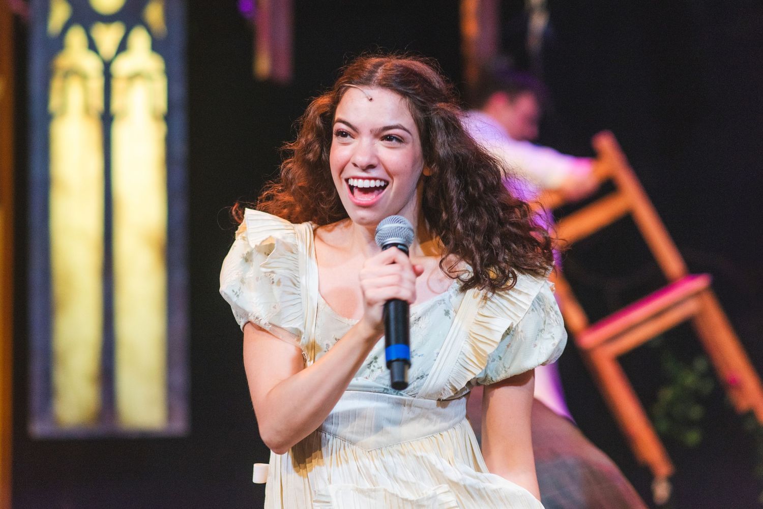 A photo from a production of Spring Awakening. The actress is holding a microphone.