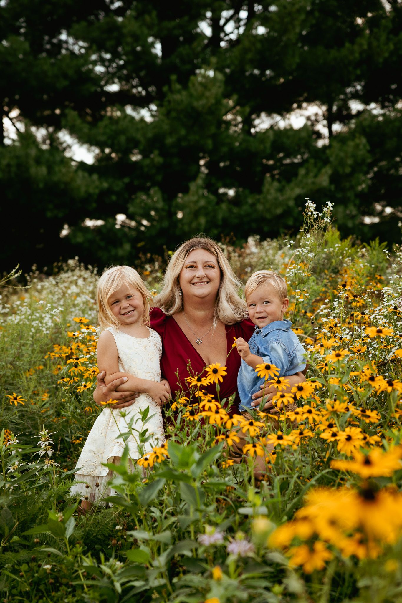 A group sits together in a vibrant field of yellow and orange wildflowers with lush green trees in the background.