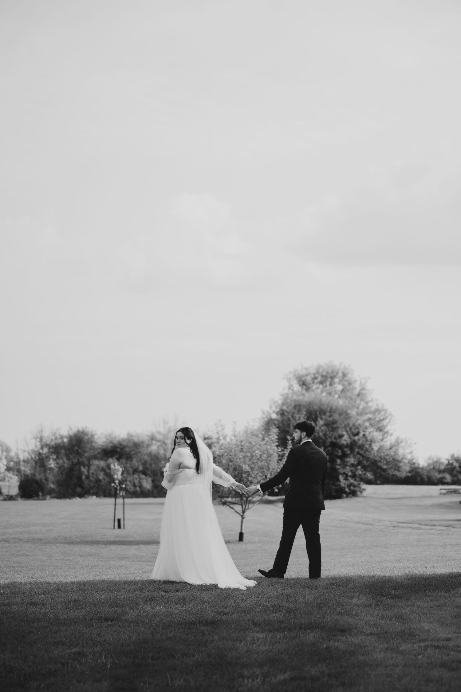 A black and white wedding photo sequence shows a couple walking across an open field in four progressive frames.