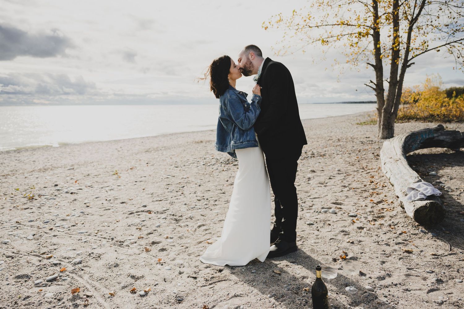 A couple shares romantic moments on a sandy beach during an autumn engagement photo session.