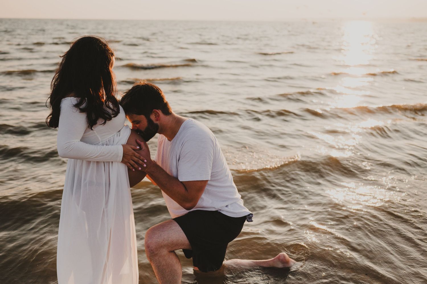 A romantic seaside proposal scene at sunset with gentle waves in the background.