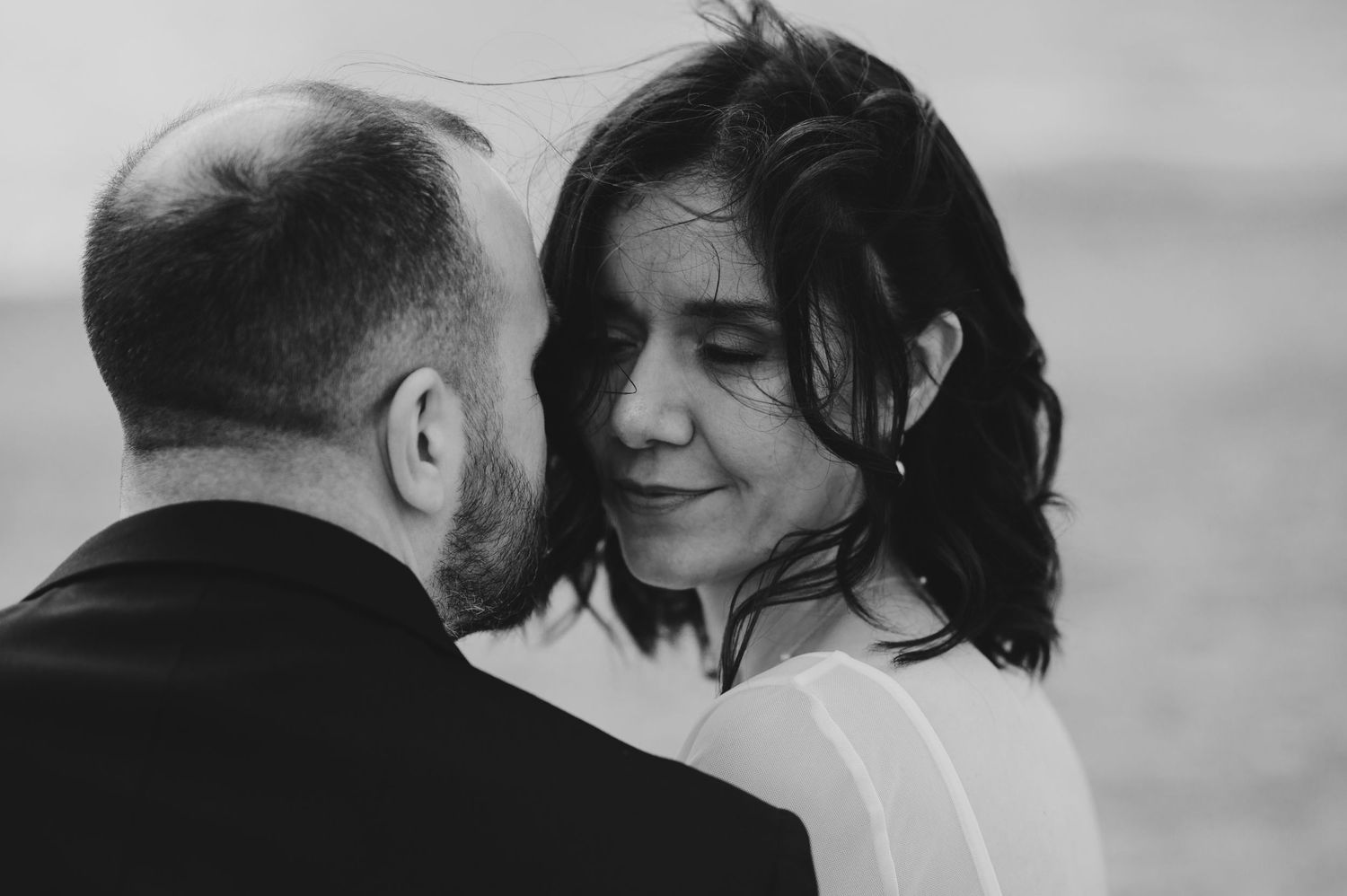 Black and white photos show romantic moments between a couple embracing and kissing at sunset.