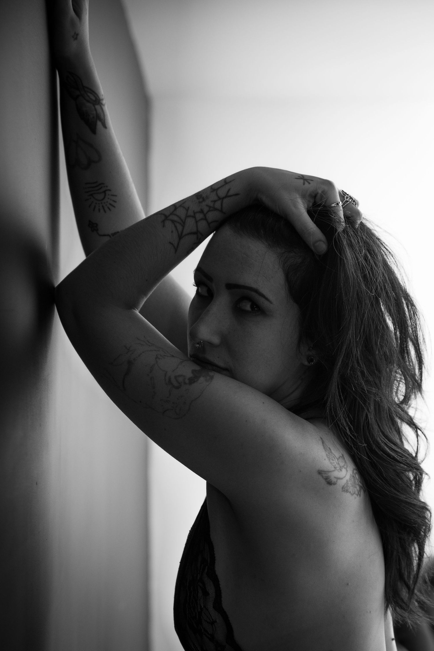 Artistic black and white portrait showing tattooed arm and shoulder.