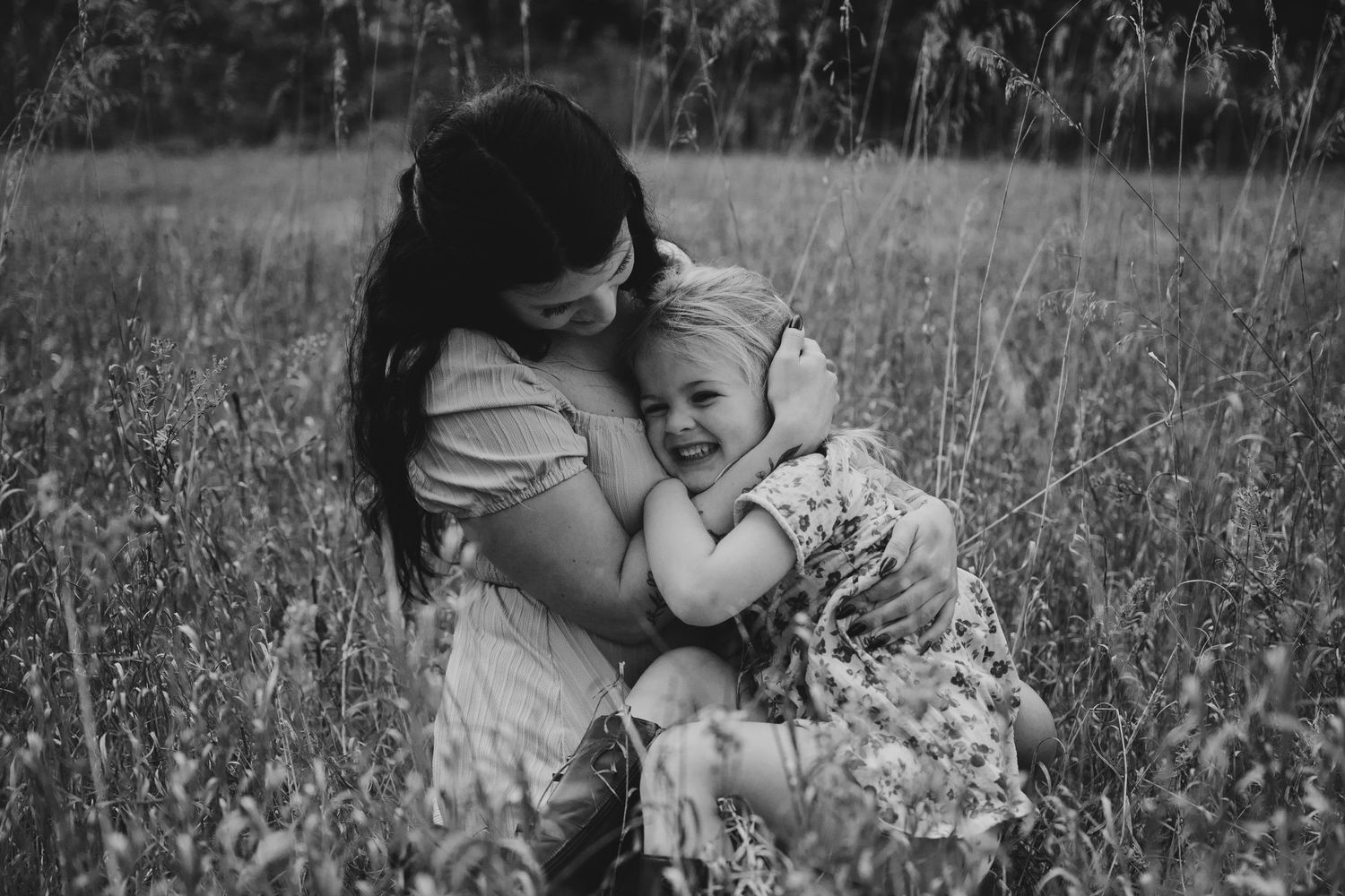Black and white photo series showing tender moments between parent and child in a wildflower meadow.