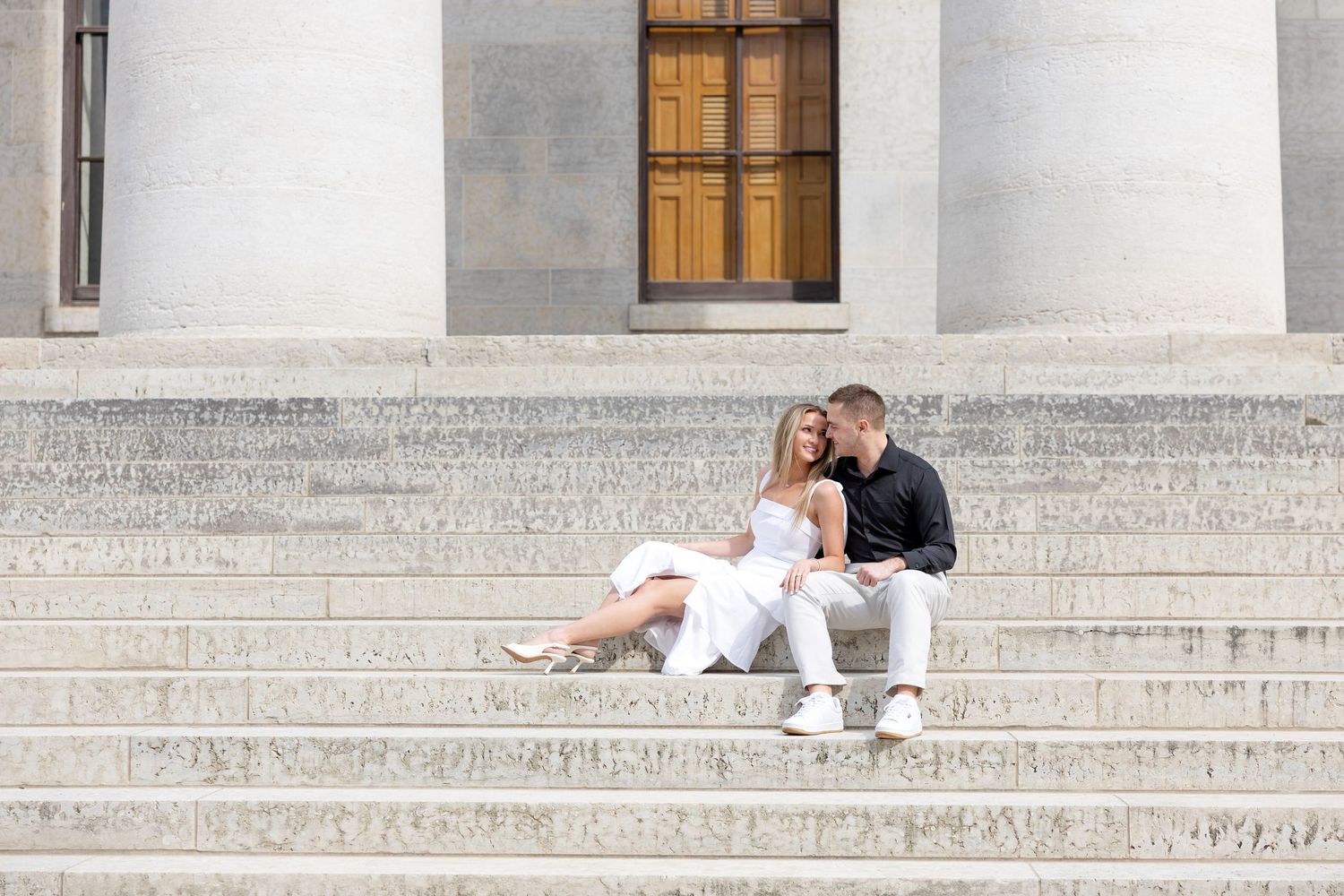 Light and airy engagement photos of a joyful couple at the Ohio Statehouse in downtown Columbus, Ohio captured by Julia and Sean Photography