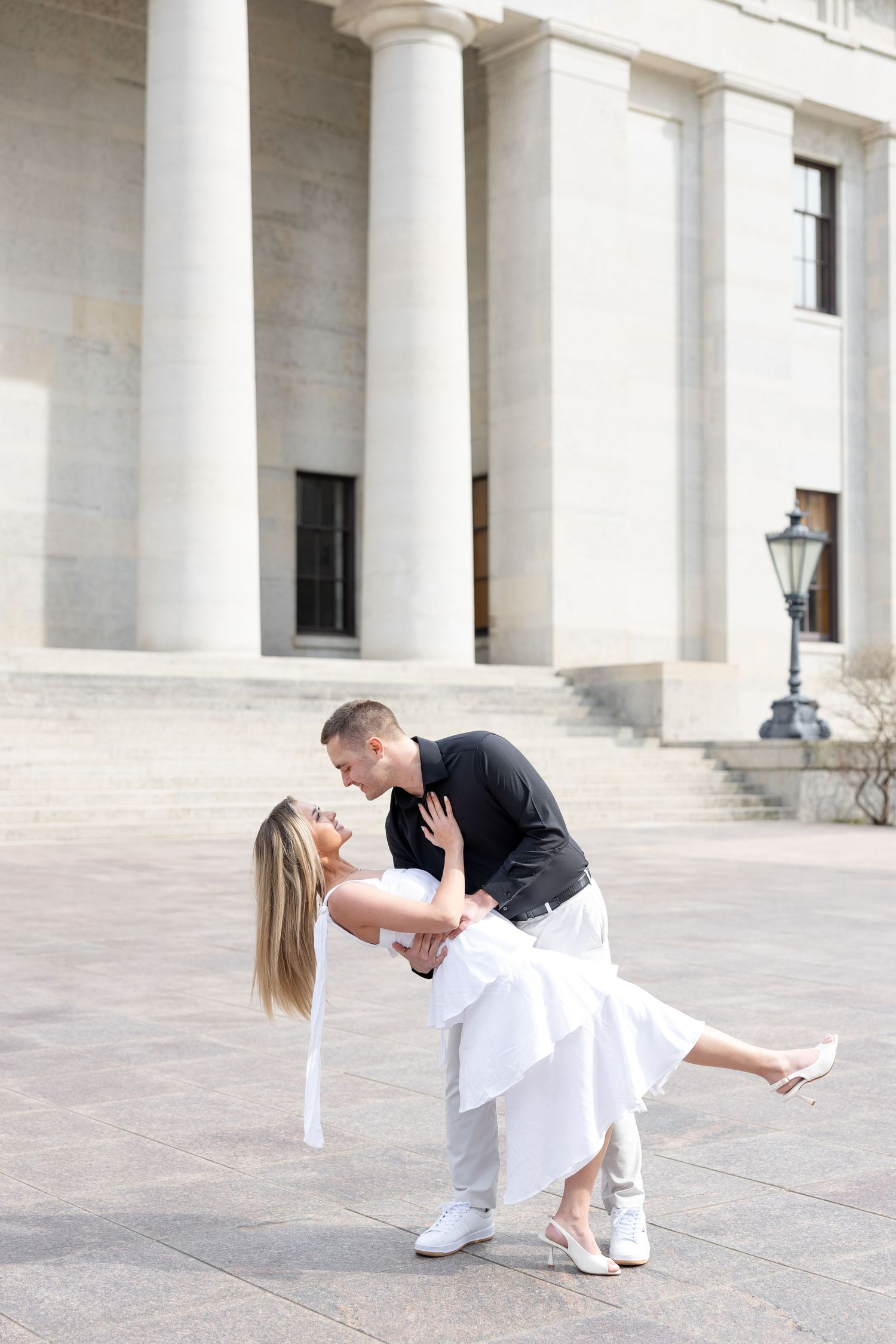 Light and airy engagement photos of a joyful couple at the Ohio Statehouse in downtown Columbus, Ohio captured by Julia and Sean Photography