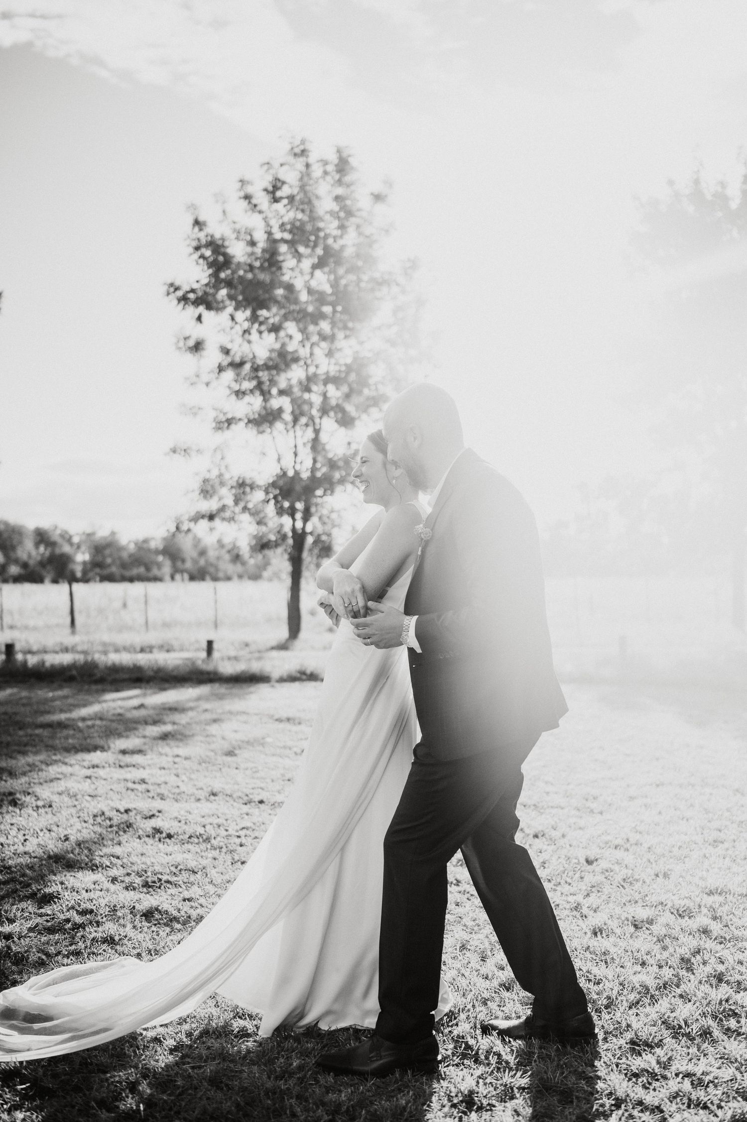 A romantic black and white wedding photo sequence showing a couple embracing in a sunlit meadow.