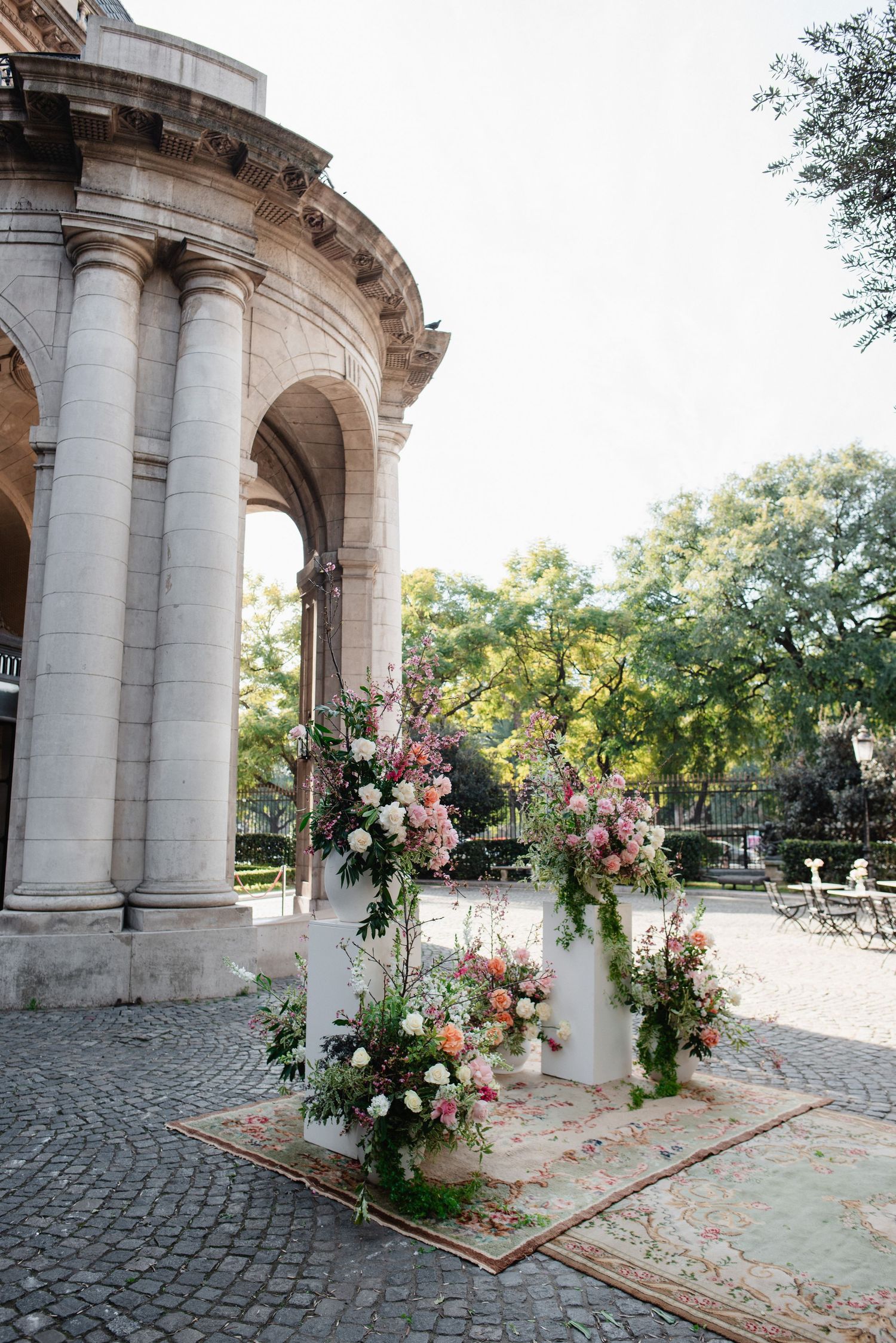 Elegant stone archway with pink and white floral arrangements decorating a cobblestone path at a wedding venue.