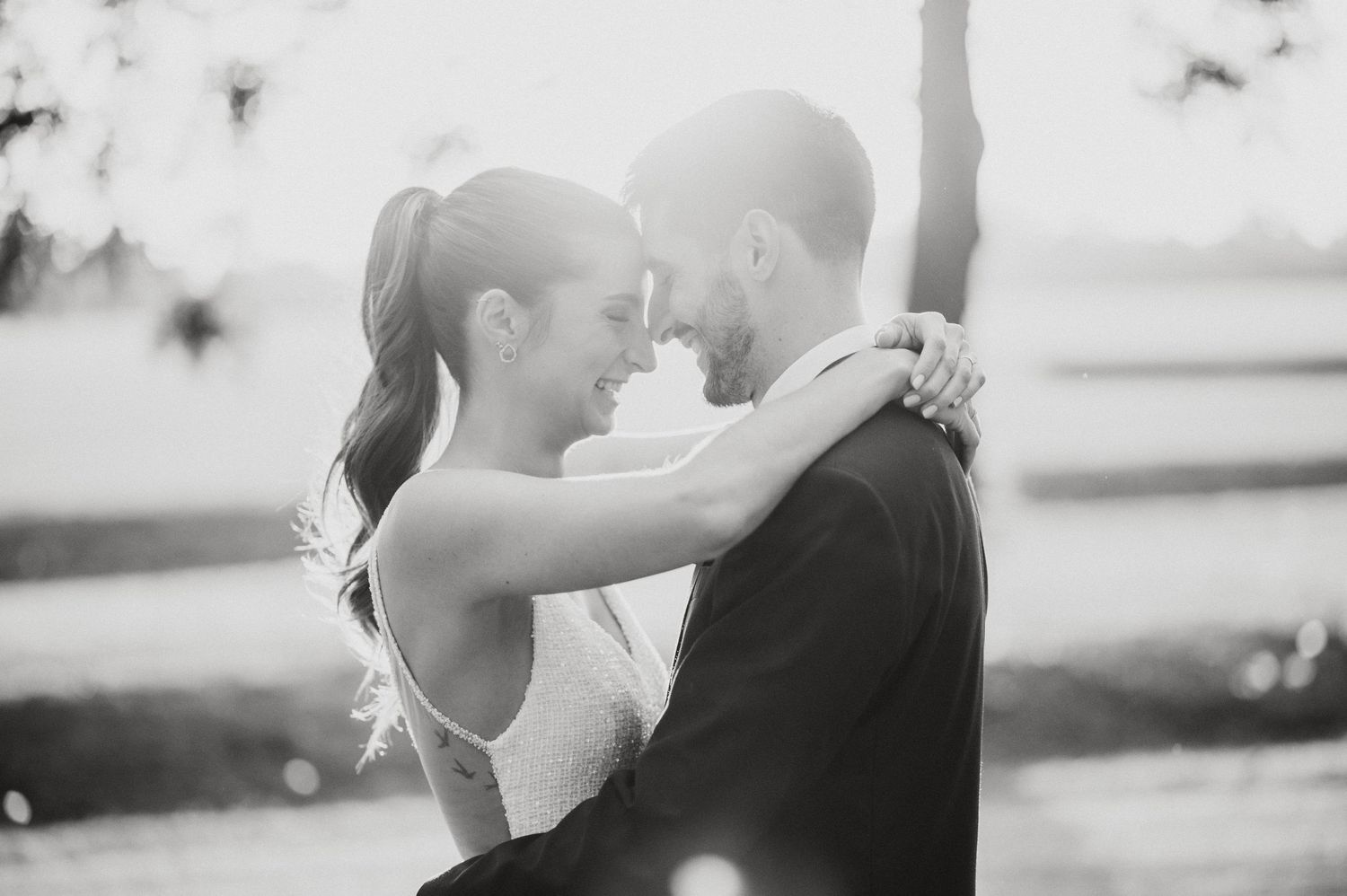 A romantic black and white wedding photo series showing intimate moments between newlyweds during sunset.