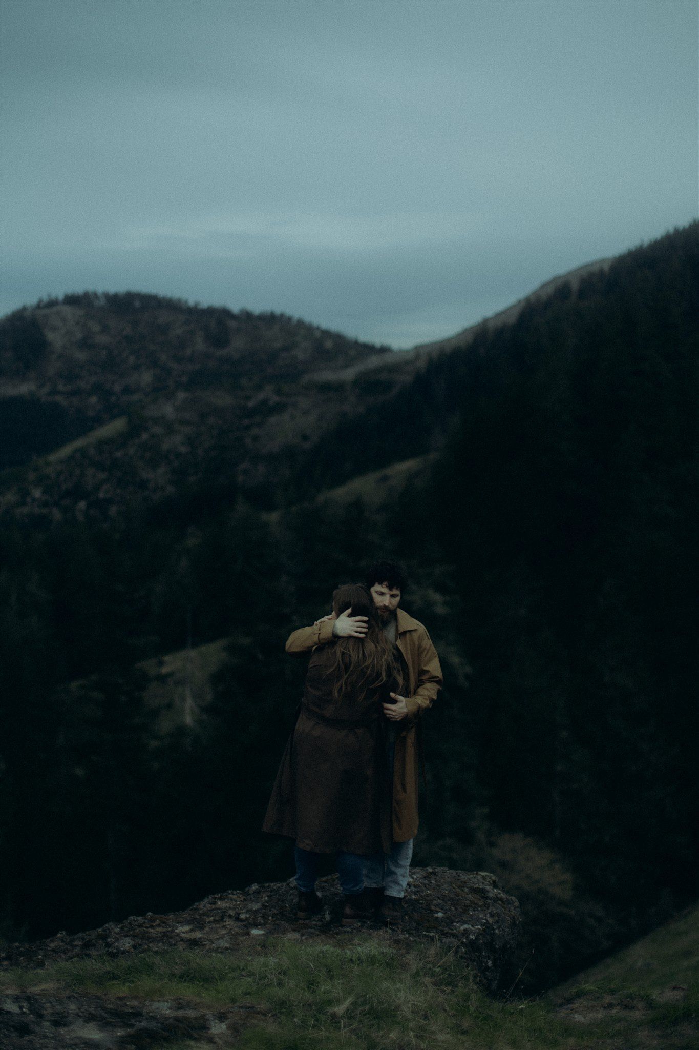 Moody landscape photograph of figures on a rocky hillside against dark mountains captured by a destination elopement photographer.