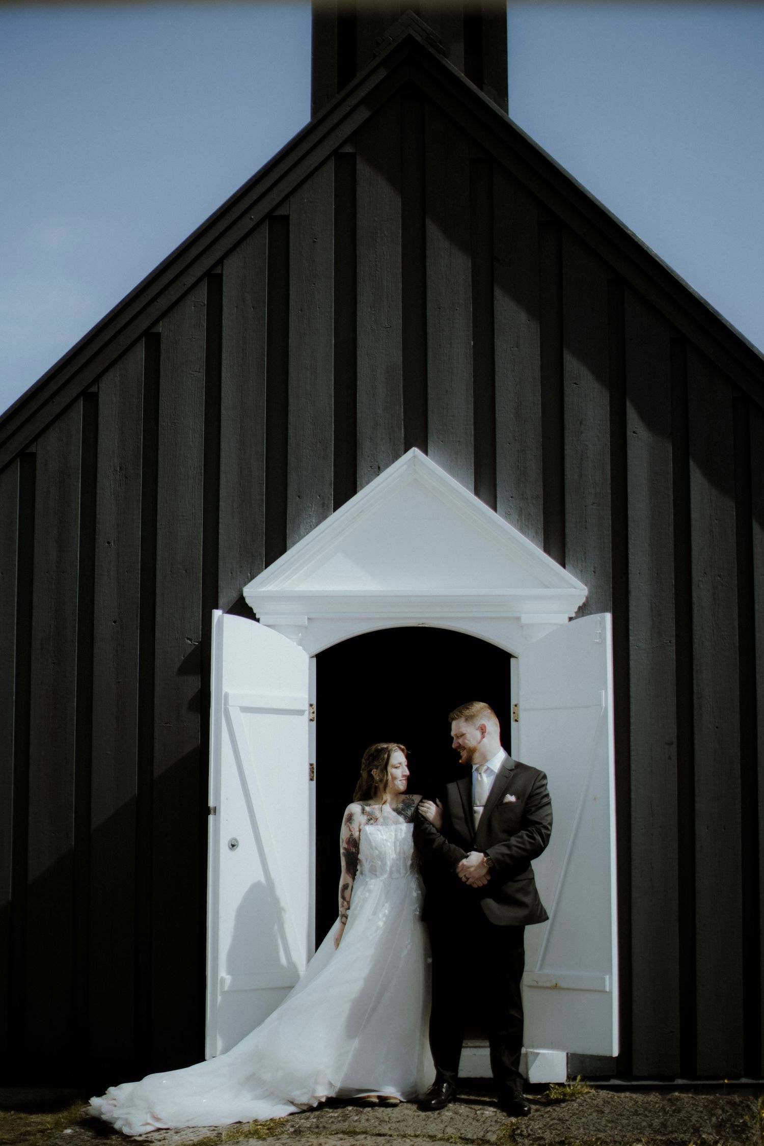 A dramatic black and white wedding photo sequence showing silhouettes against a modern church building exterior.
