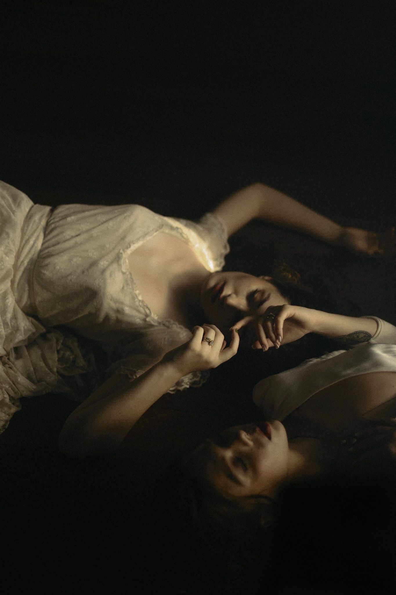 A figure lies in darkness under white sheets in a dramatic and moody lighting setup.