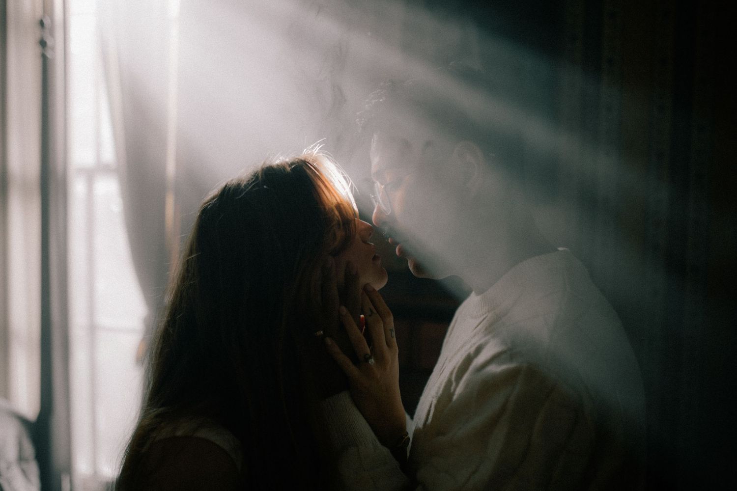 Light streams through a window illuminating silhouettes in a dark moody setting.