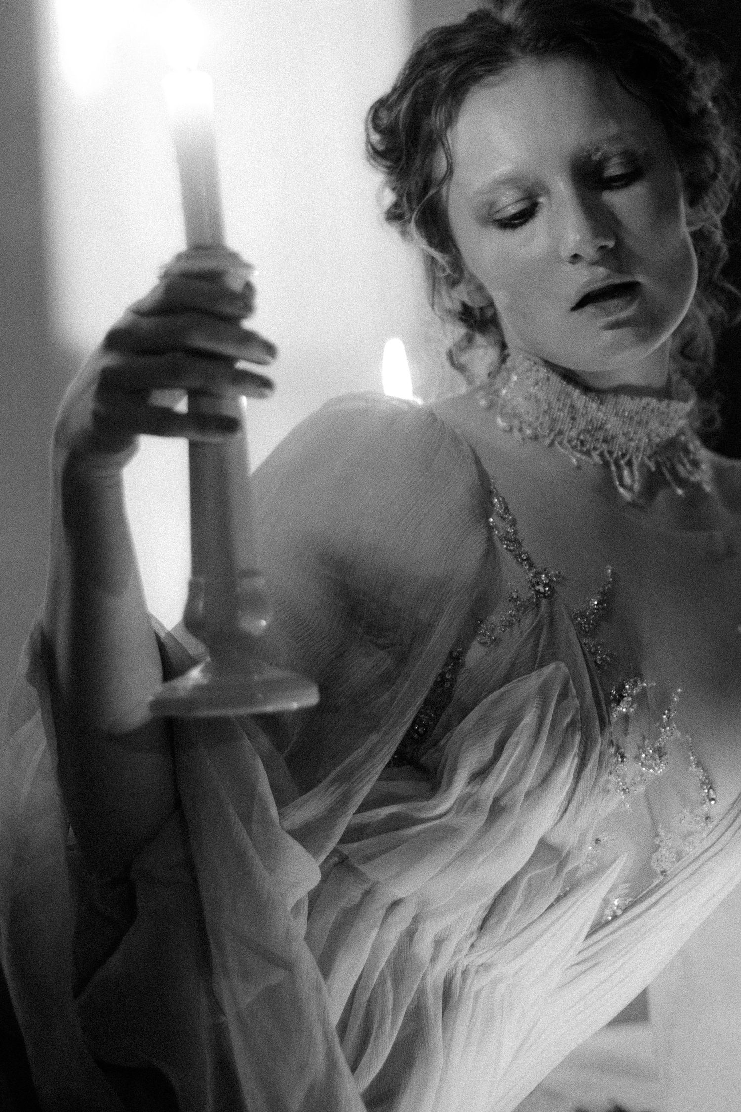 A black and white artistic portrait showing a person in flowing white fabric with dramatic lighting and ethereal mood.