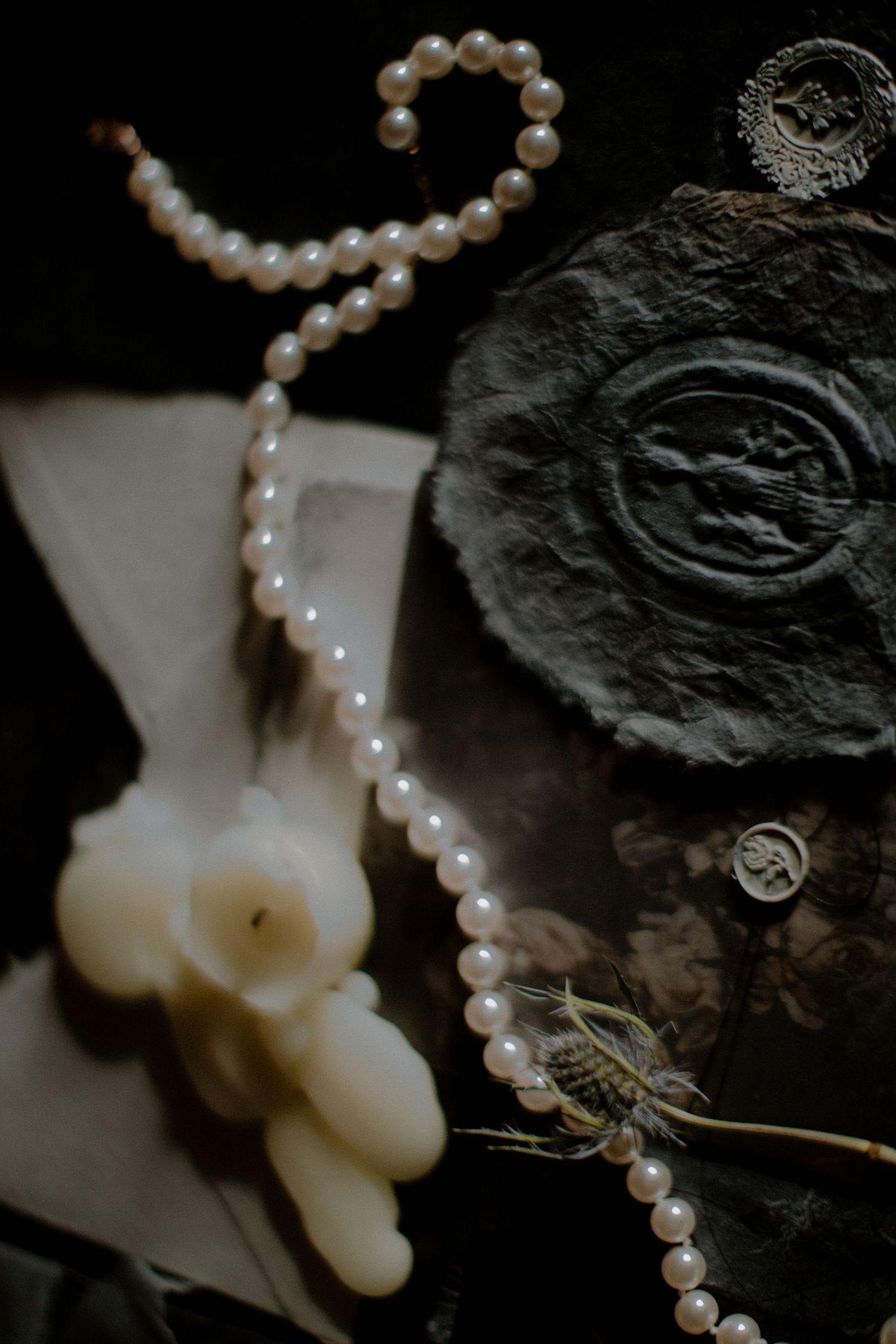 A string of lustrous white pearls draped elegantly across a dark textured background with vintage aesthetic details.