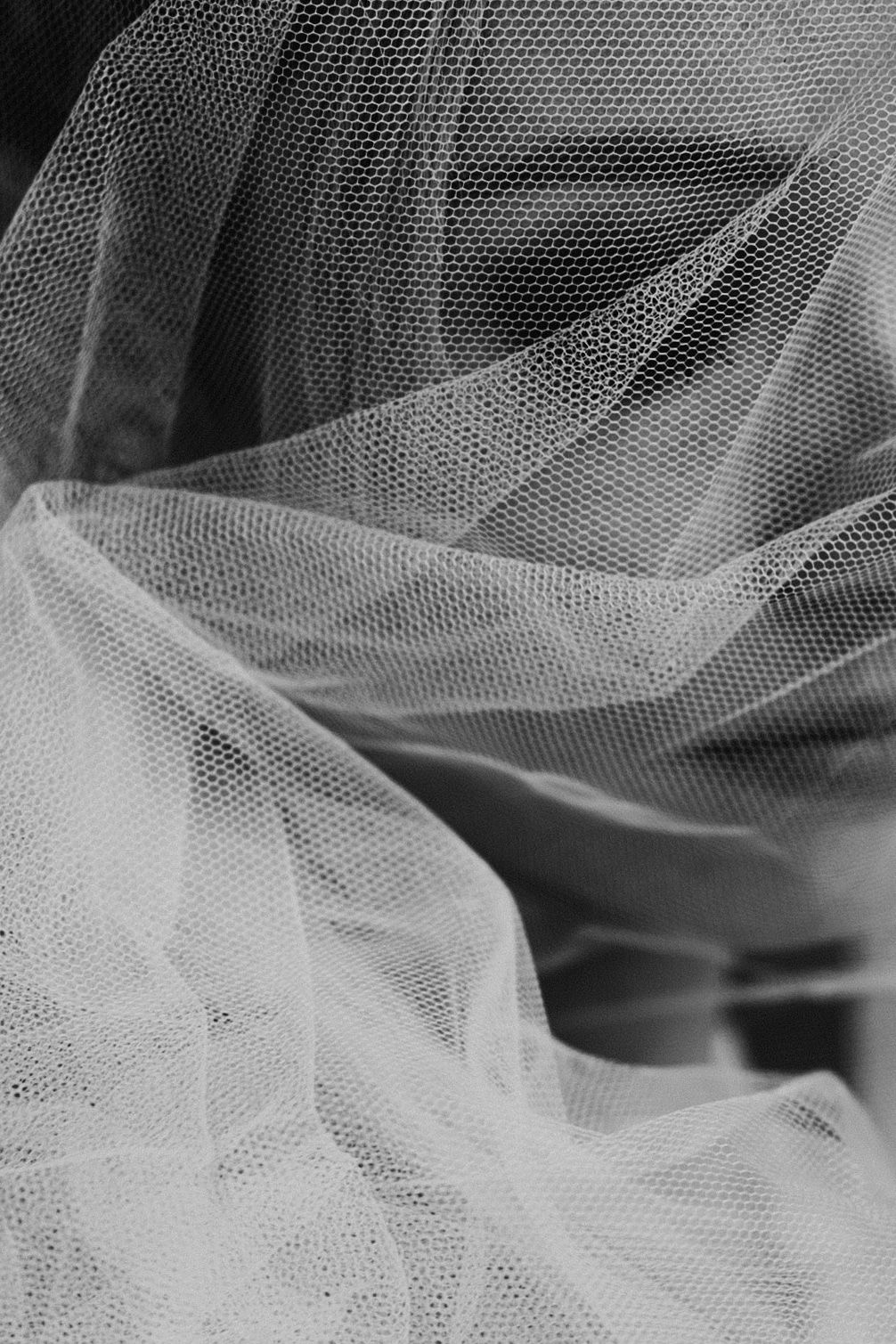 Black and white close-up of flowing tulle fabric with delicate mesh texture and soft draped layers.