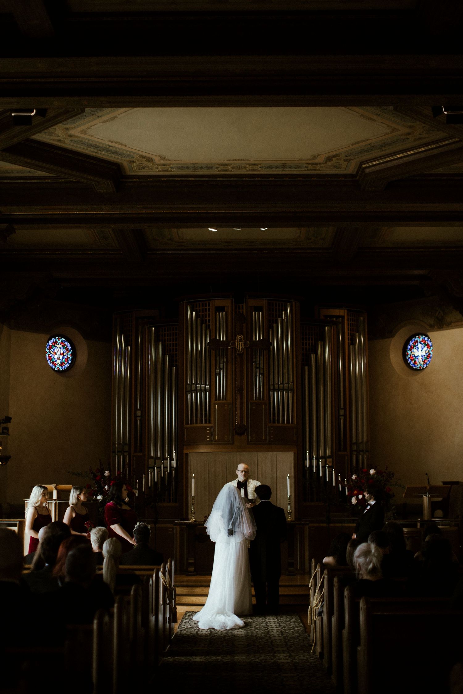 Dramatic silhouette of a wedding ceremony in a dark church with pipe organ.