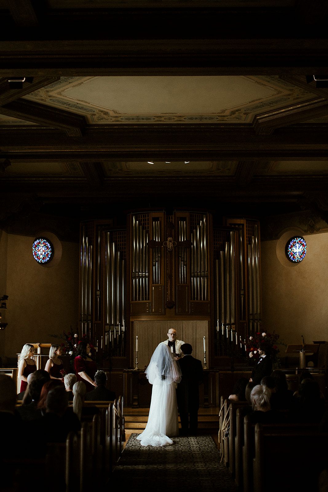 A series of dark, moody wedding ceremony photos in a church with dramatic lighting and pipe organ backdrop.