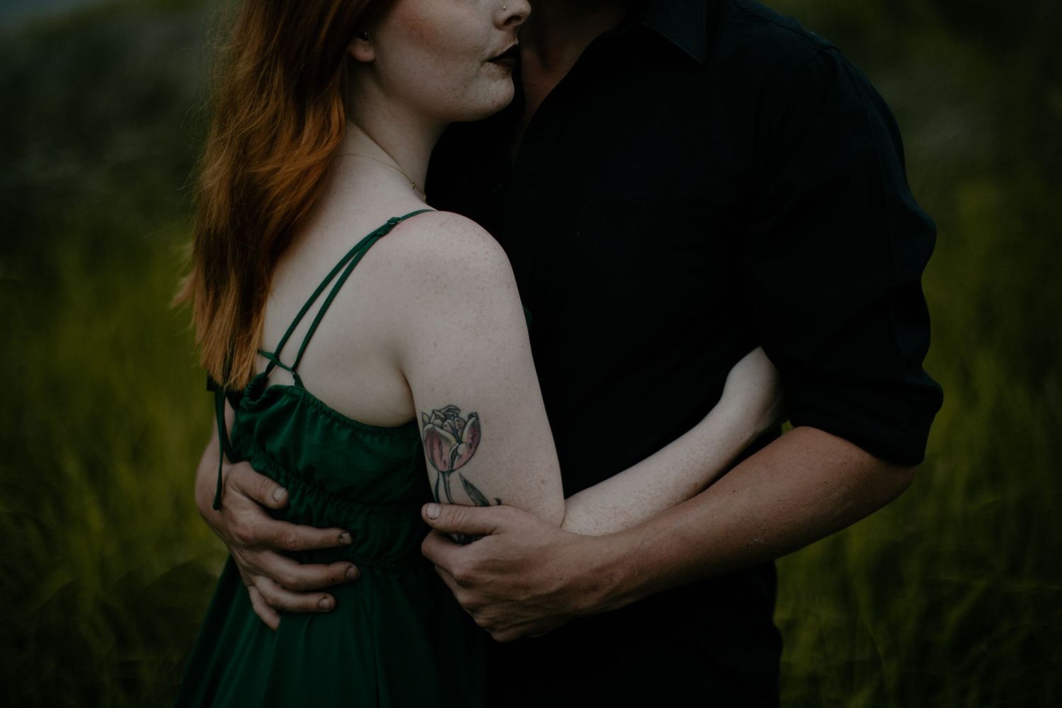 Intimate couple embrace against natural outdoor backdrop.