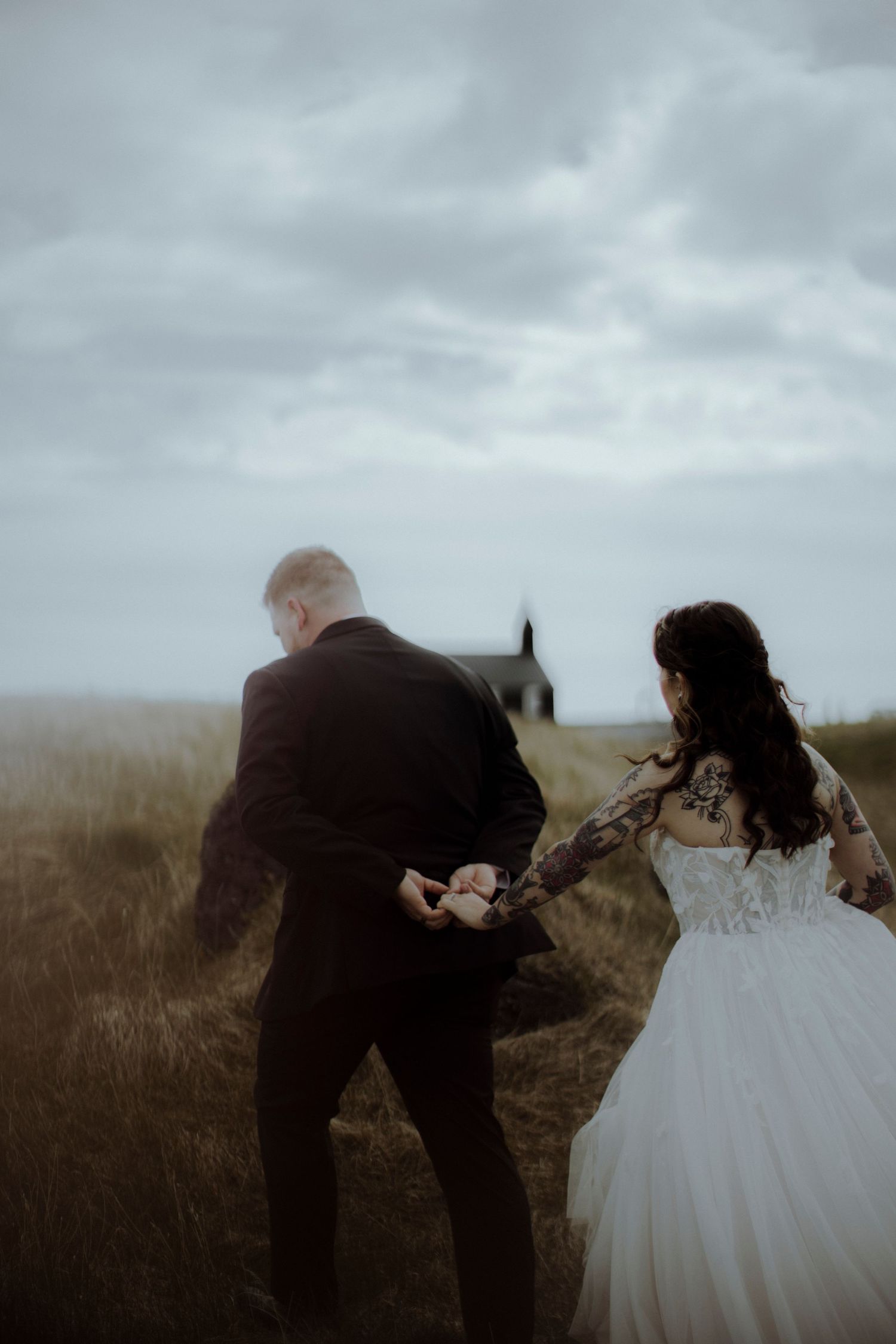 A couple in formal wear dance together on a windswept hilltop.