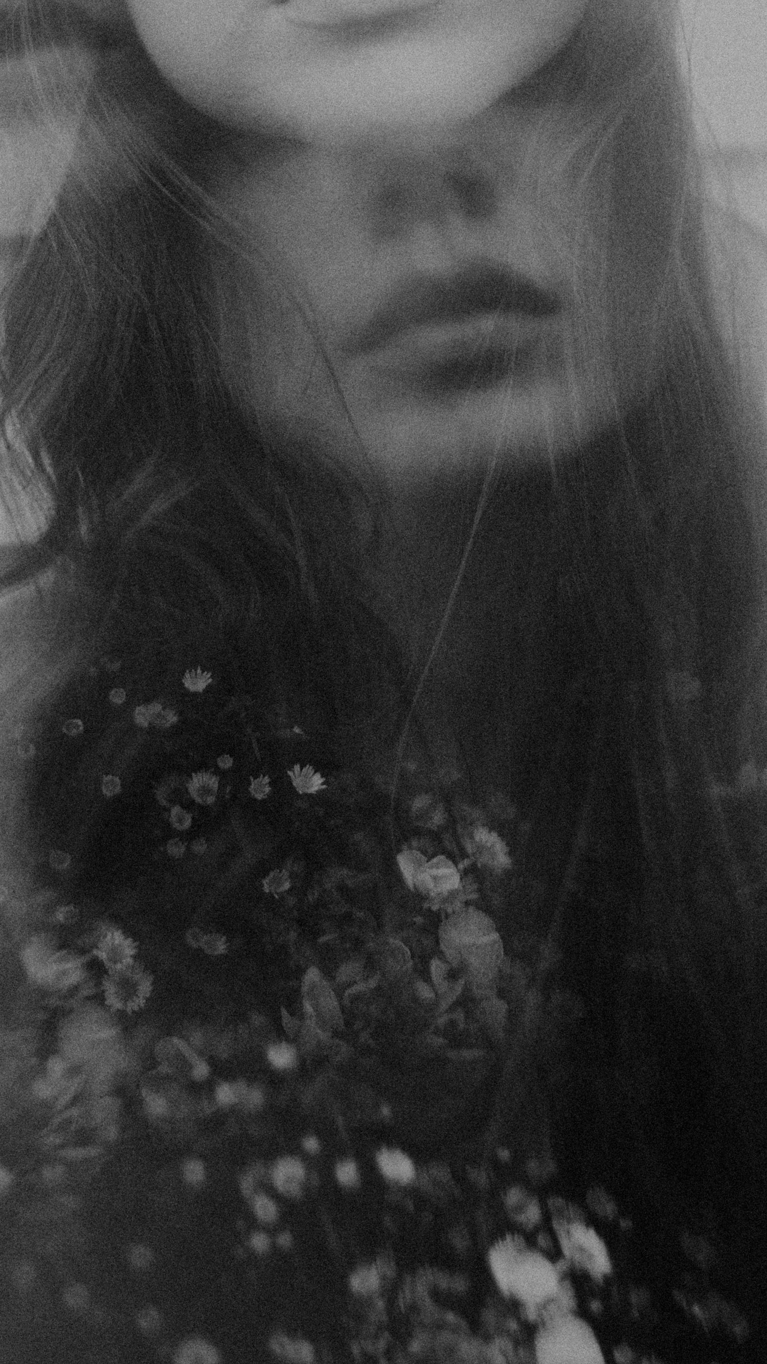 Dreamy black and white portrait with soft focus flowers in the foreground.