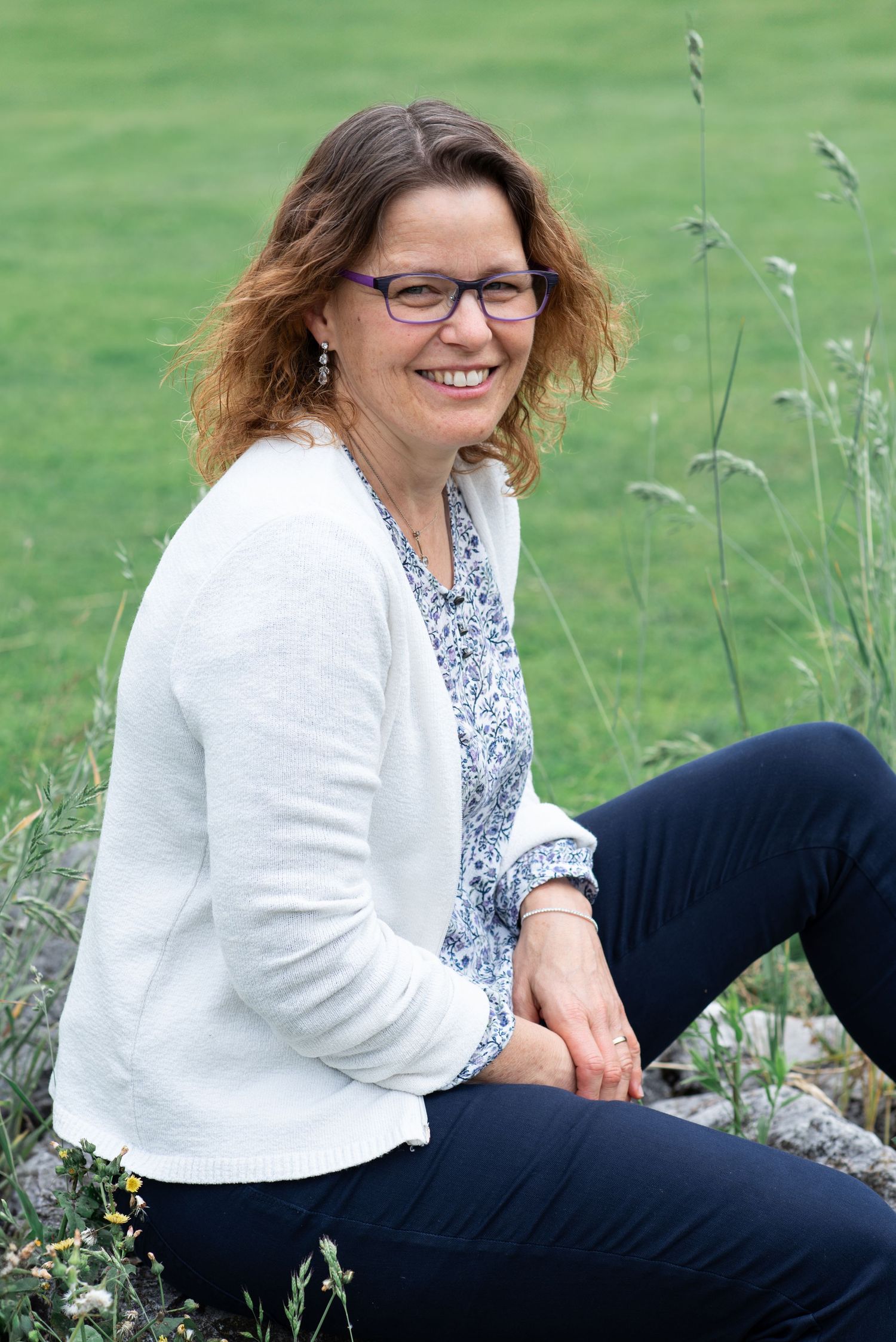 Someone relaxing outdoors in casual attire against a natural green background.