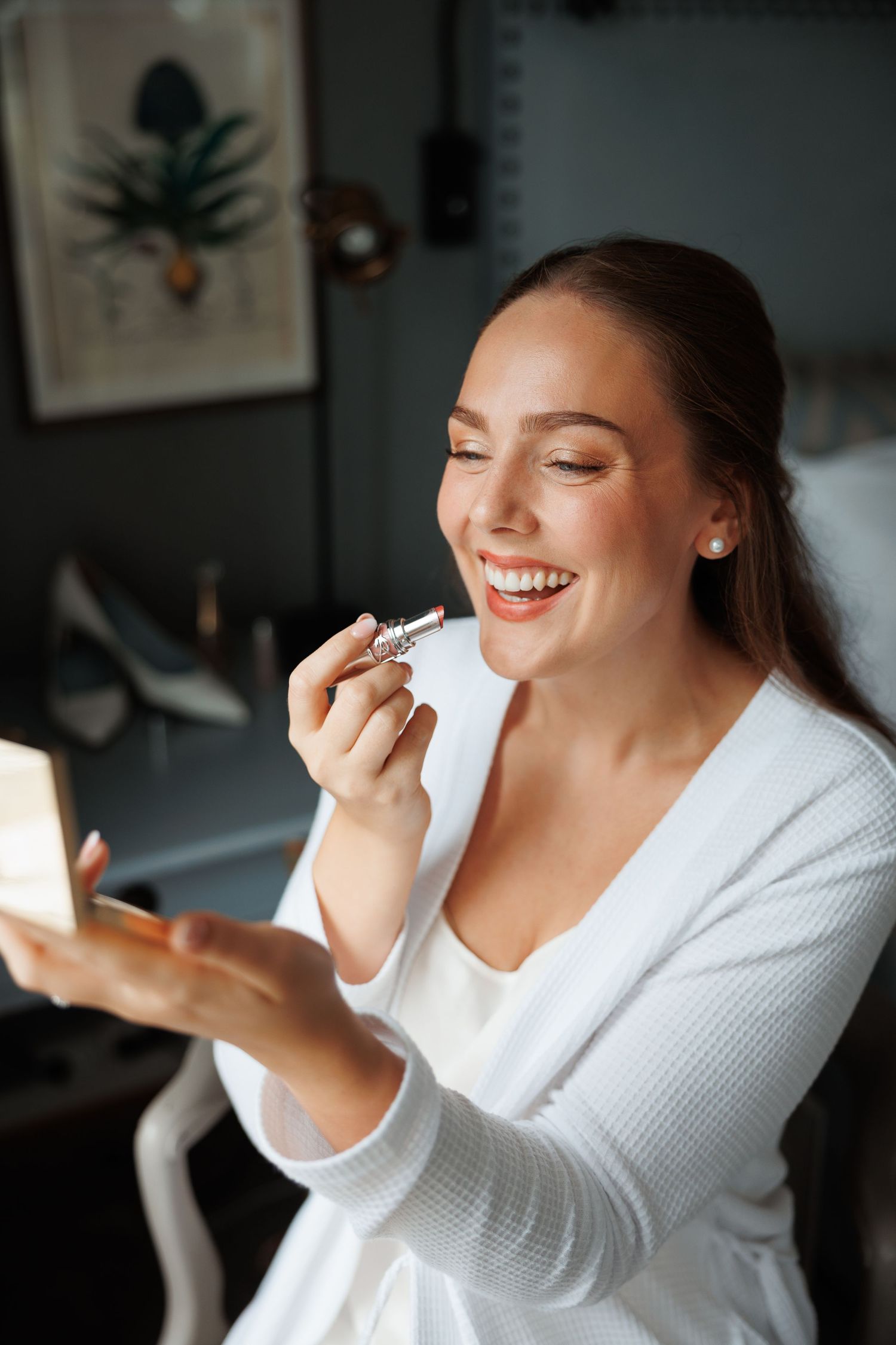 Person in white bathrobe enjoying joyful moment at home with natural lighting through window.