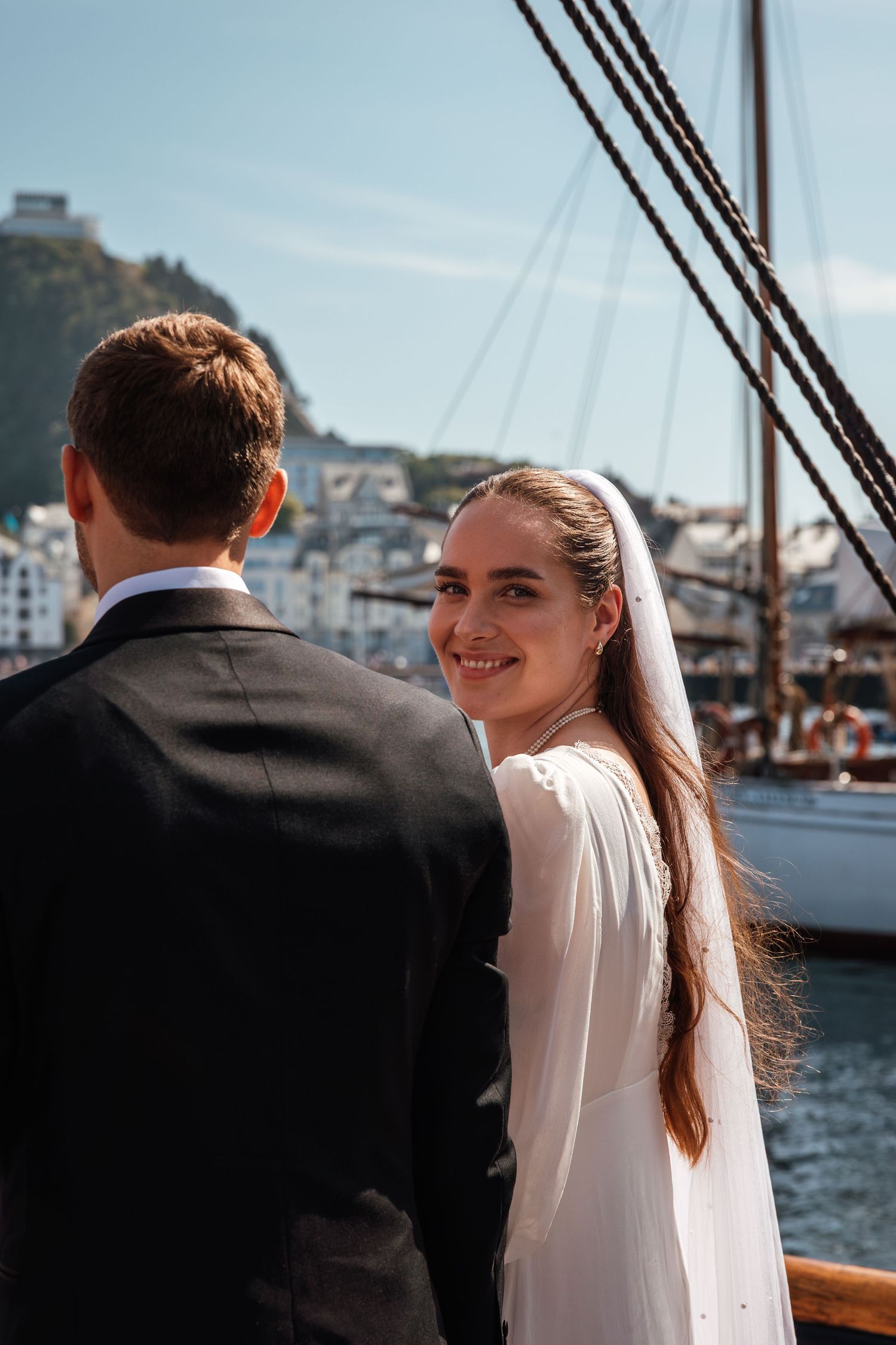 A couple enjoying a romantic moment on a boat with a harbor view in the background.