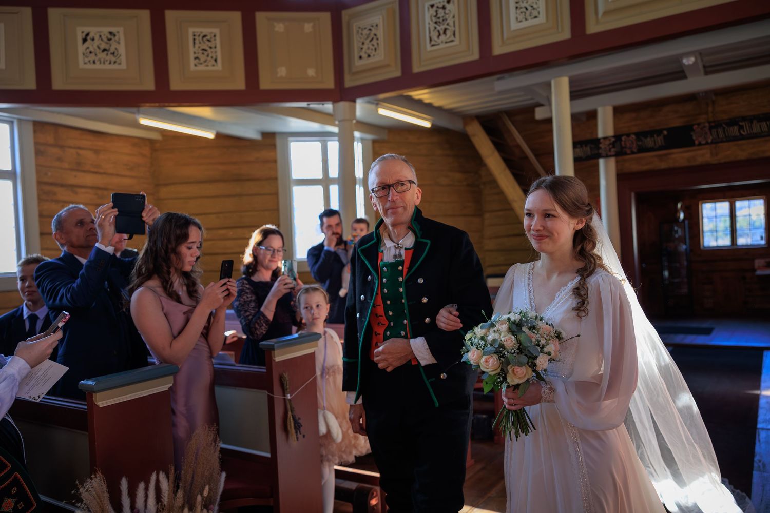 Wedding ceremony in rustic wooden church with guests and decorative framed artwork on walls.