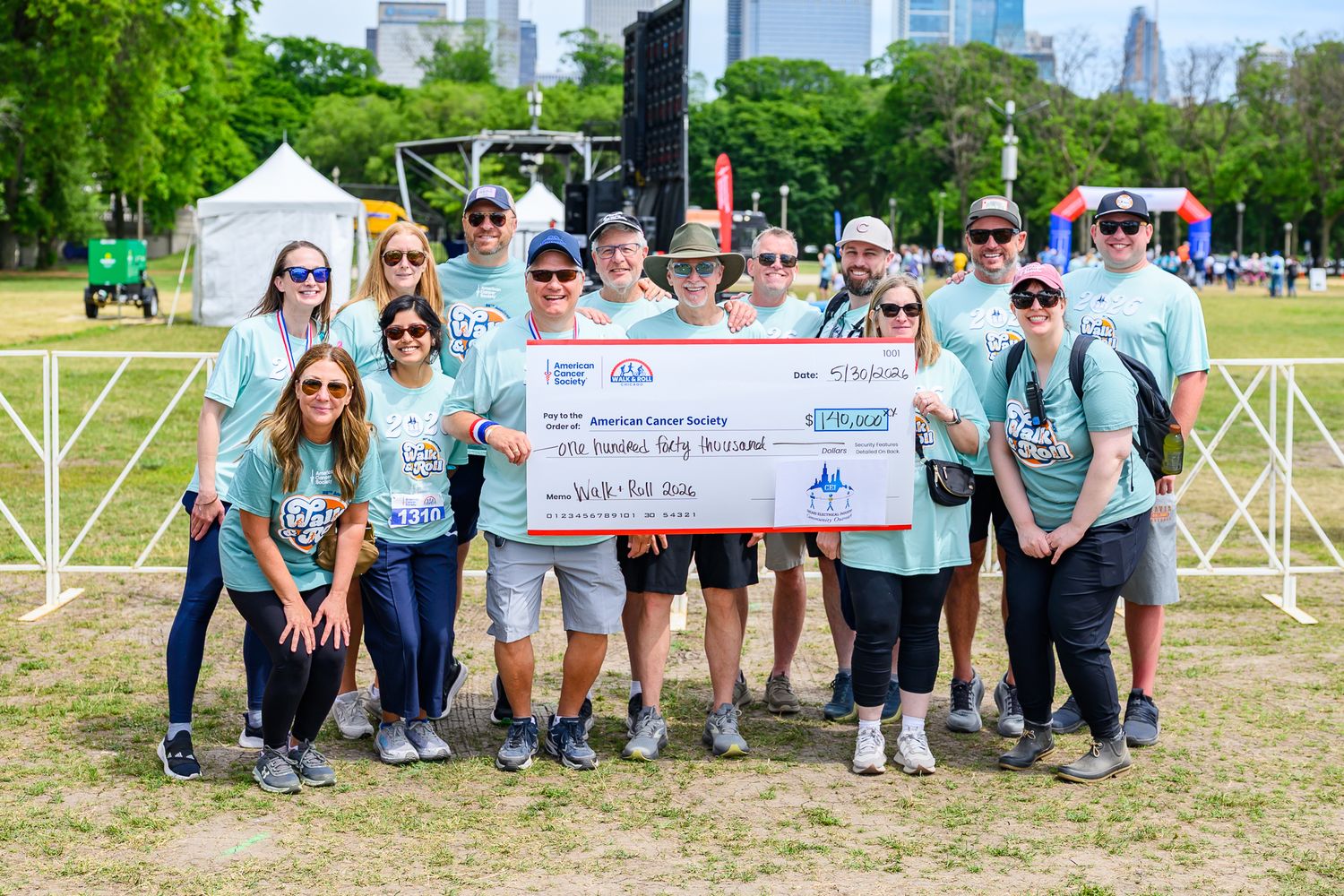 Group holds large donation check at American Cancer Society Walk & Roll charity event.