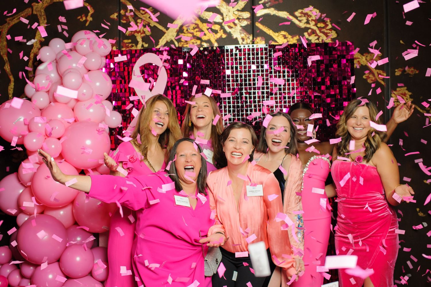 Celebration with pink decorations and confetti showing people enjoying a festive event.