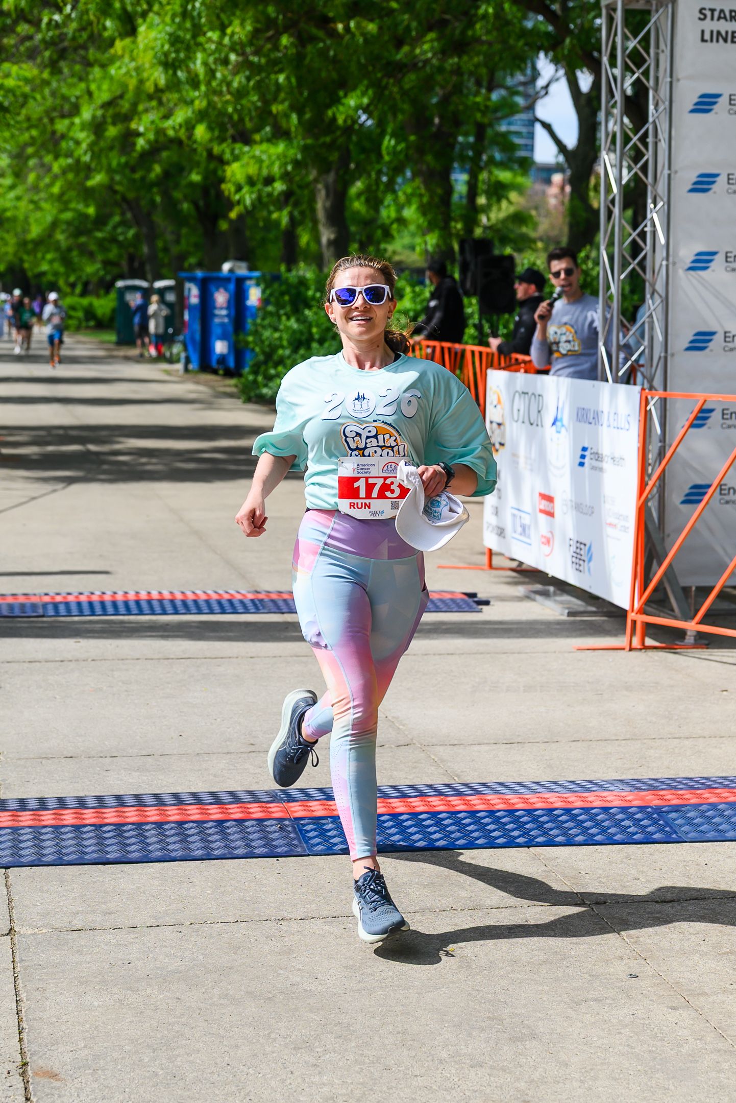 Woman in colorful leggings crosses finish line at American Cancer Society Walk and Roll 5K race.