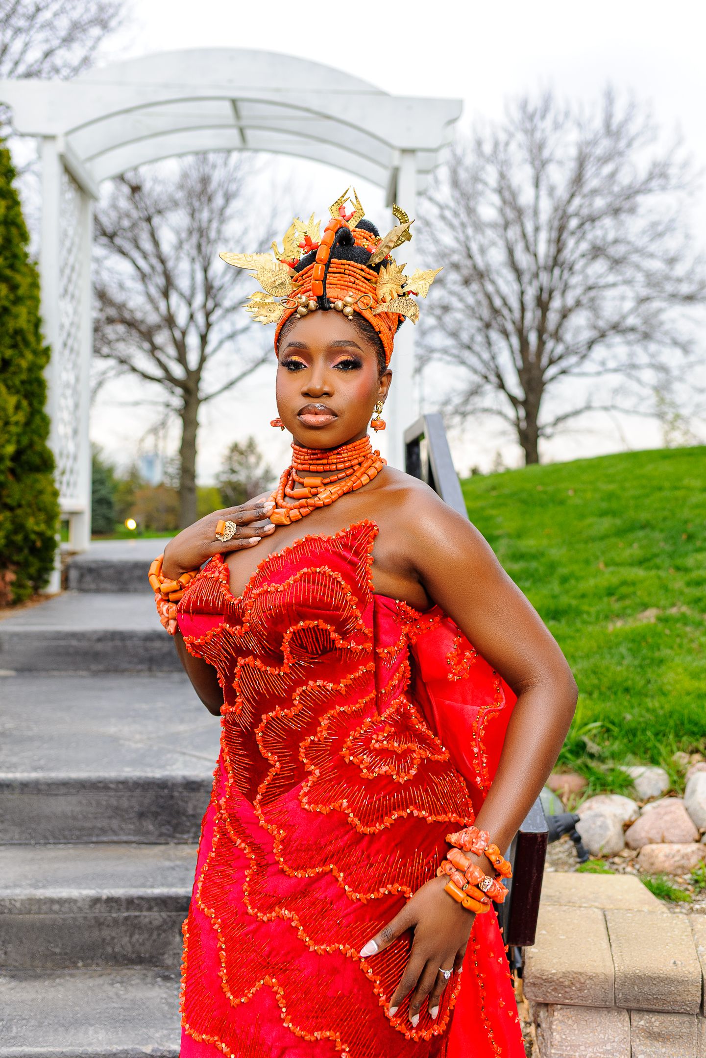 Woman in stunning red Nigerian traditional wedding dress with elaborate orange coral beaded headdress and jewelry.