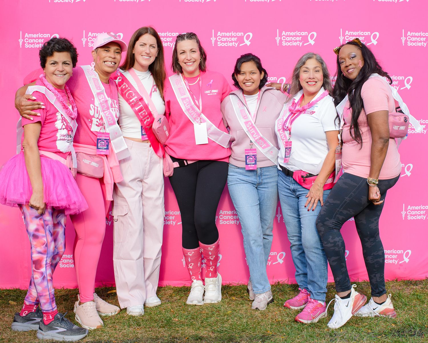 Group photo of cancer awareness event participants posing together against pink backdrop.