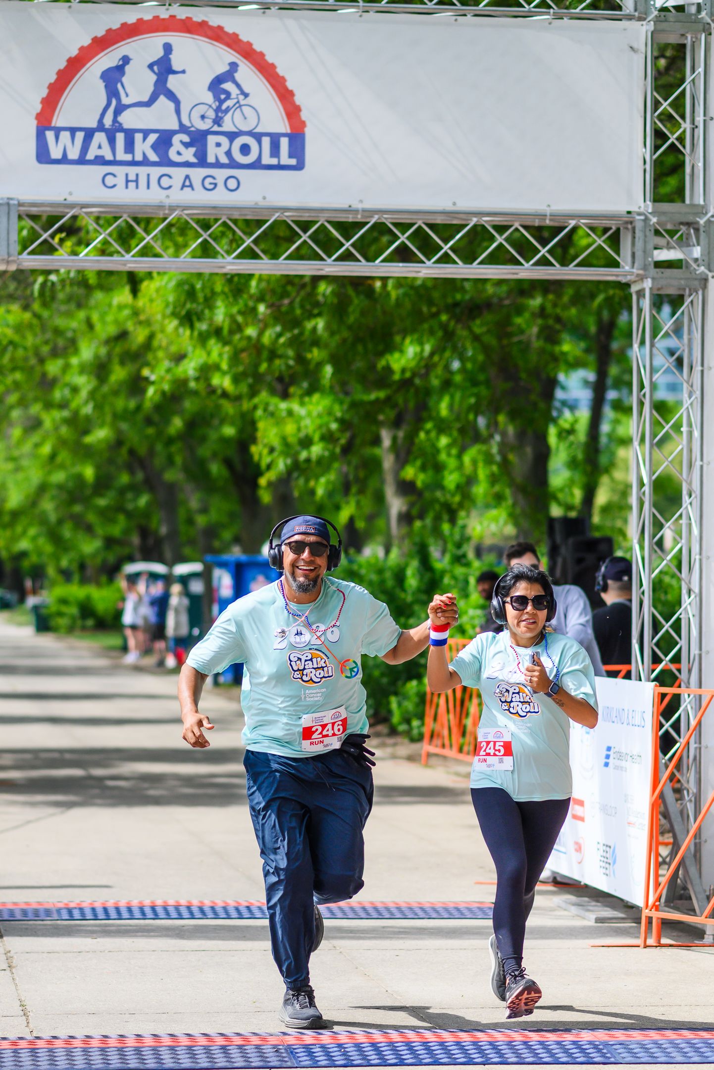 Man and woman cross finish line hand-in-hand at Walk & Roll Chicago American Cancer Society event.