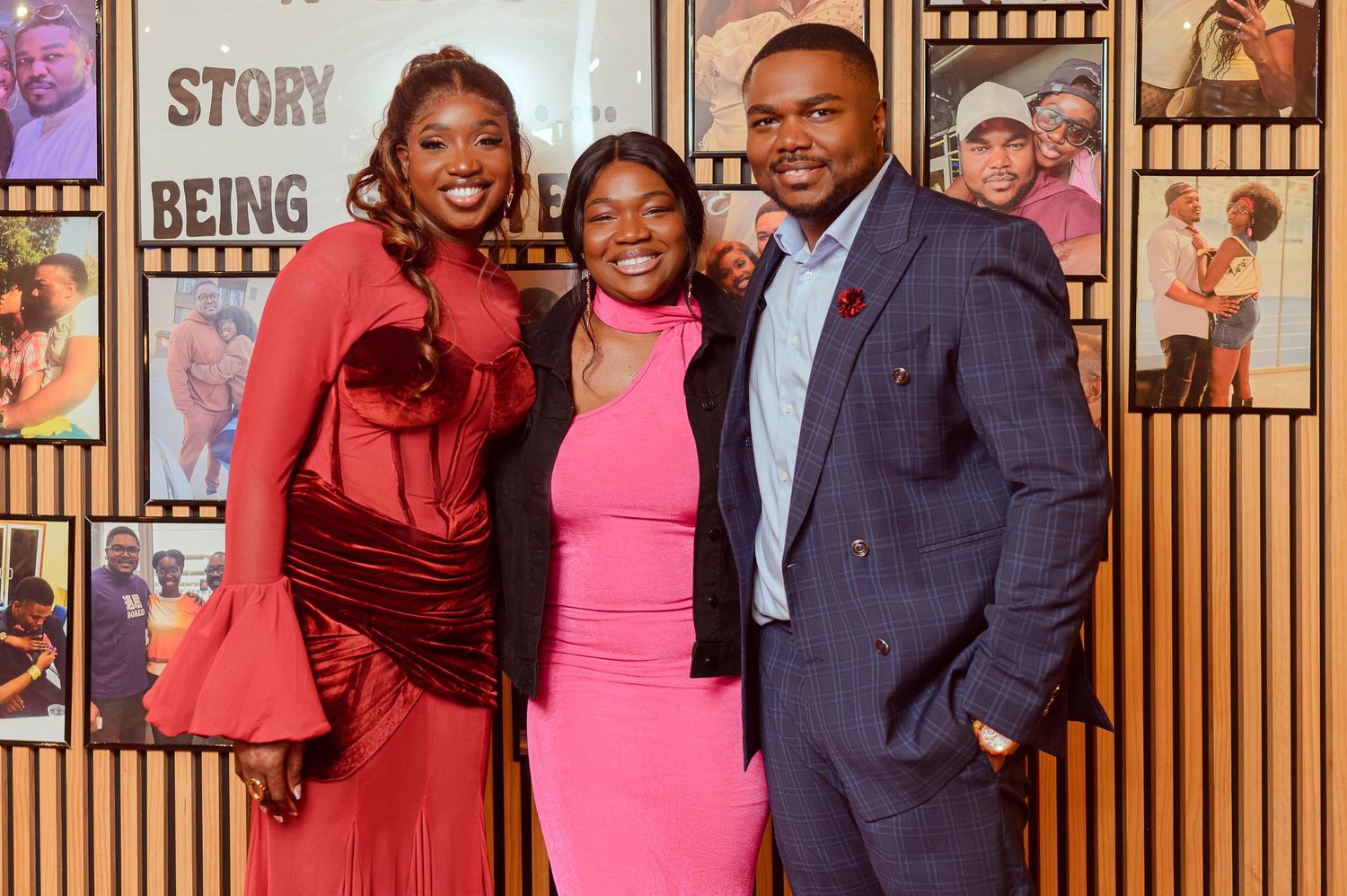Three people posing together at an event, dressed in elegant attire, standing in front of a decorative backdrop.