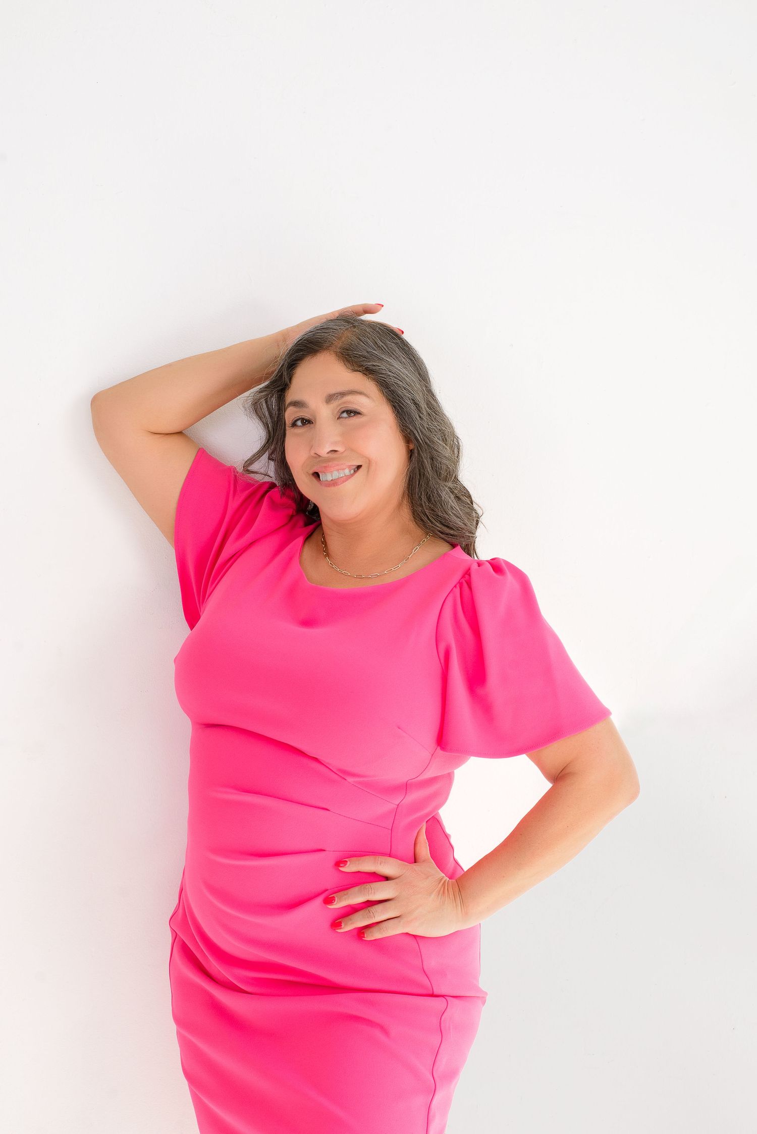 Person in bright pink dress poses playfully against white background in four sequential poses.