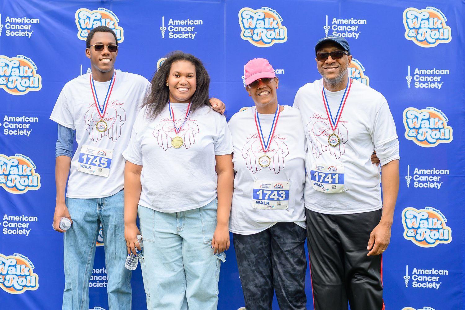Group of four participants wearing Walk & Roll American Cancer Society event shirts and medals pose together.