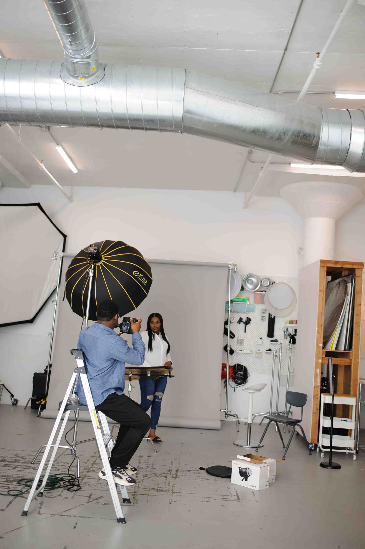 Photography studio setup with lighting equipment and ladder for professional photo shoot.