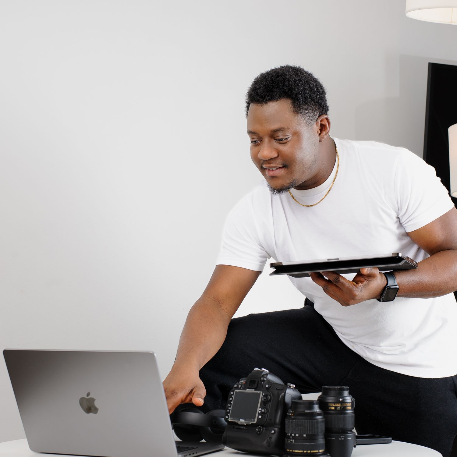 Professional photographer reviewing camera equipment and laptop while working in a studio setting.