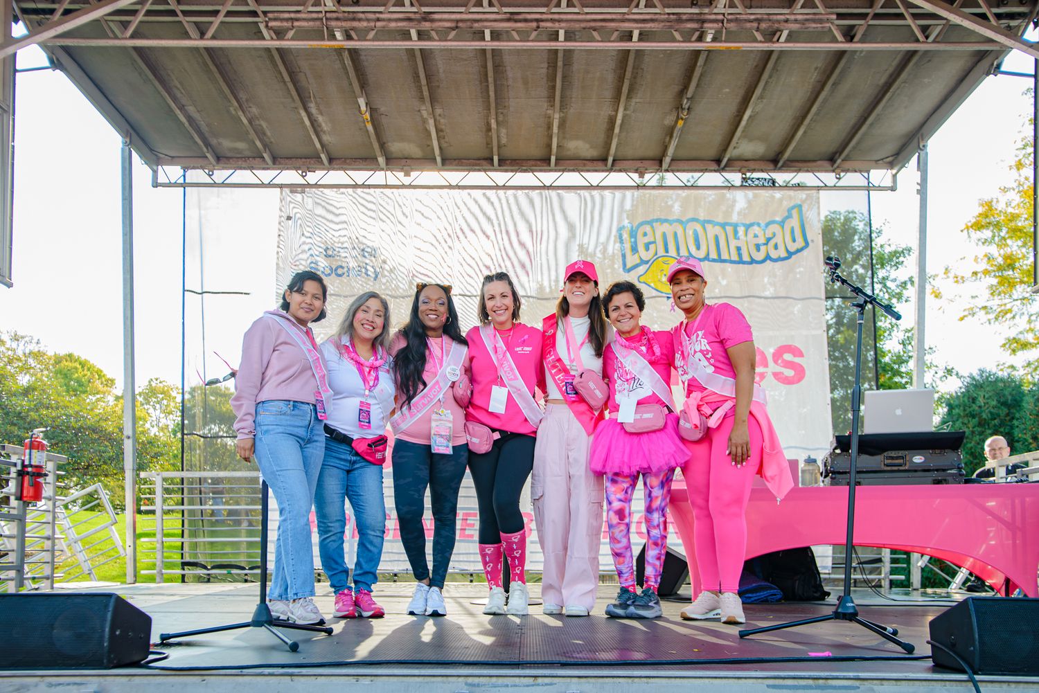 Wide shot of participants gathered on outdoor stage at charity awareness event.
