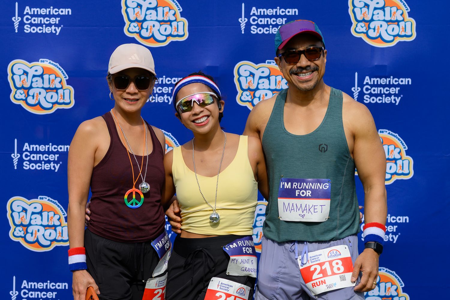 Three friends wearing race bibs pose together at American Cancer Society Walk and Roll Chicago event.