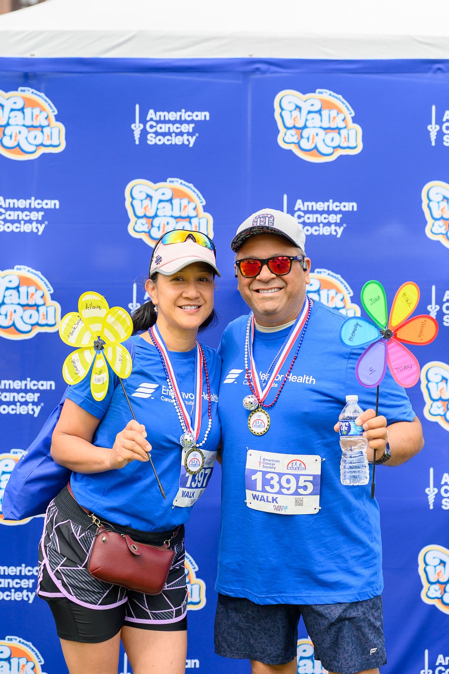 Two smiling participants wearing medals pose at American Cancer Society Walk and Roll charity event.
