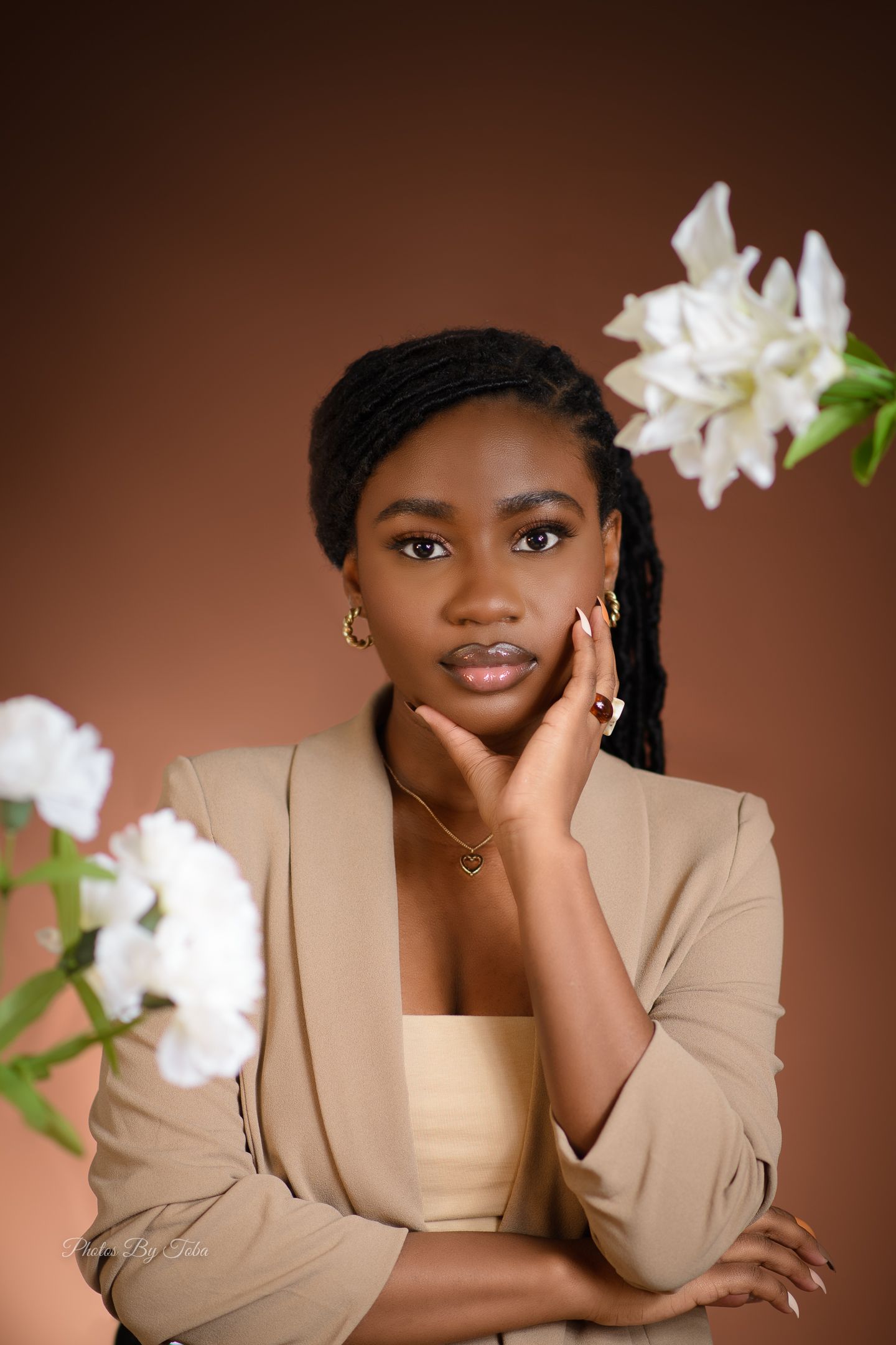 Studio portrait with white orchids against warm brown background.